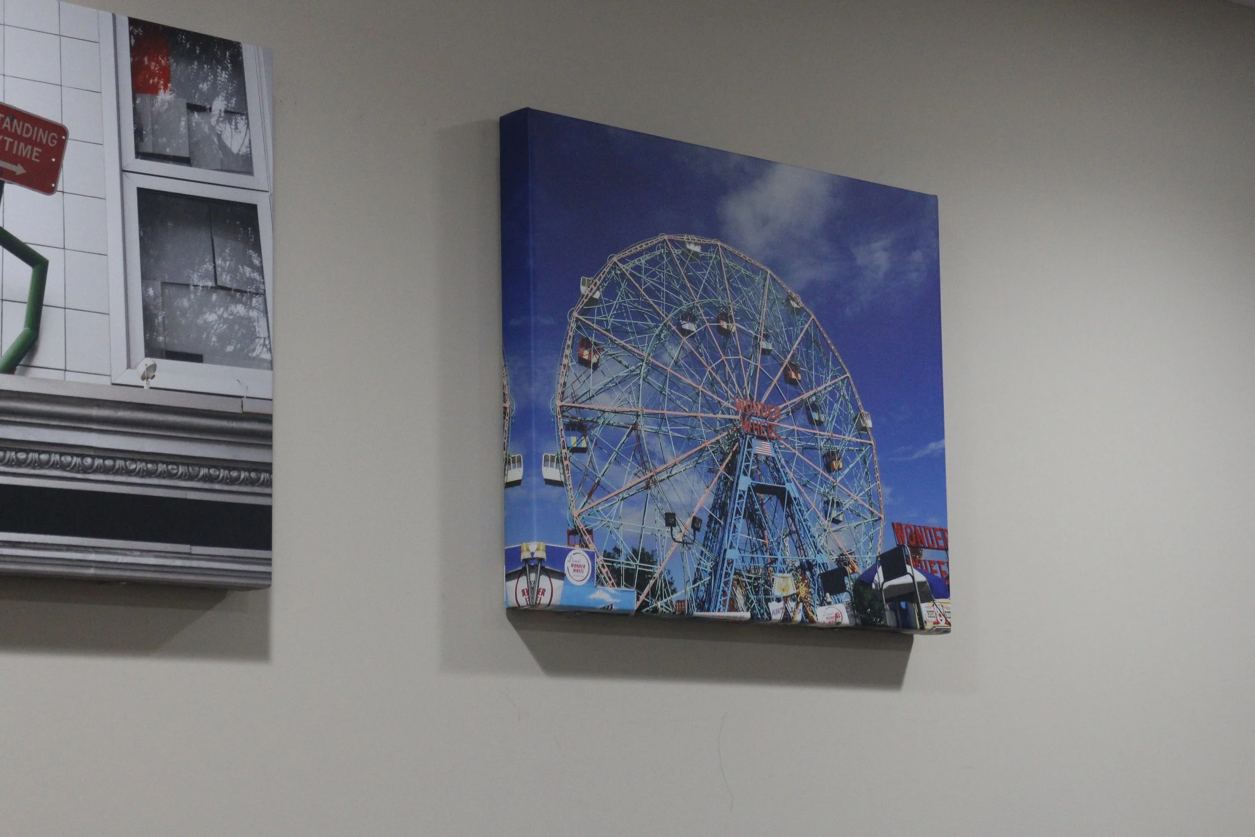Photograph of a ferris wheel at a fair or amusement park against a blue sky with some clouds.