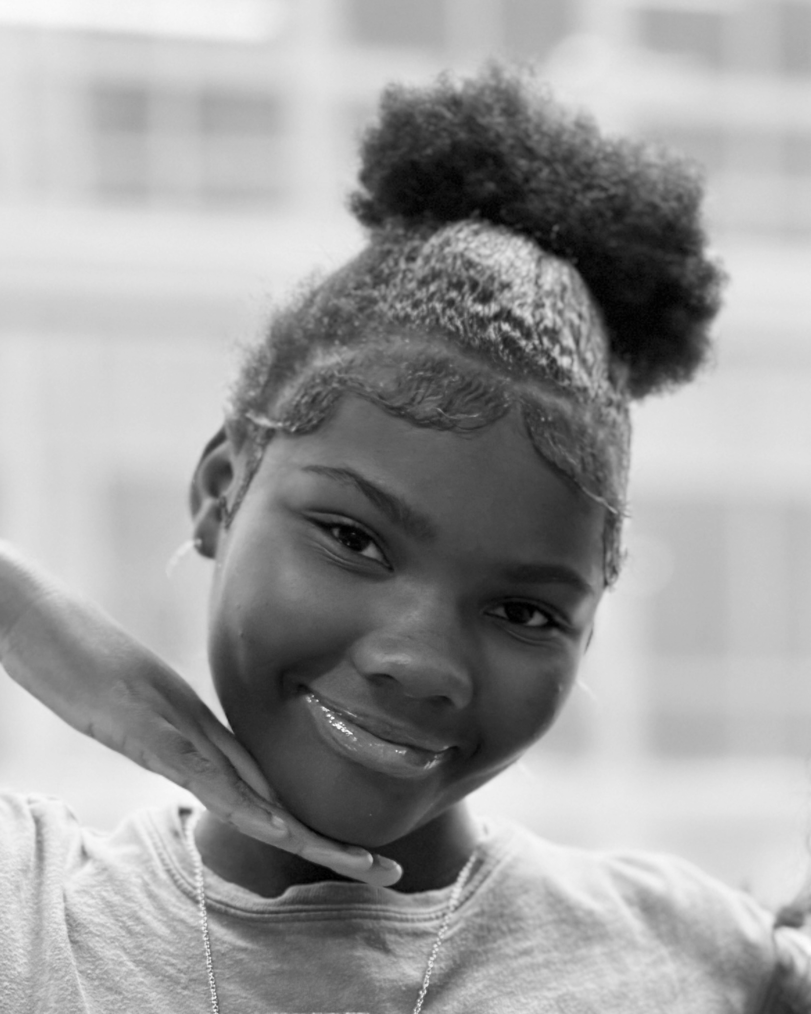 Black and white photo of a woman with braids, glasses, and a sweatshirt featuring colorful cartoon characters.