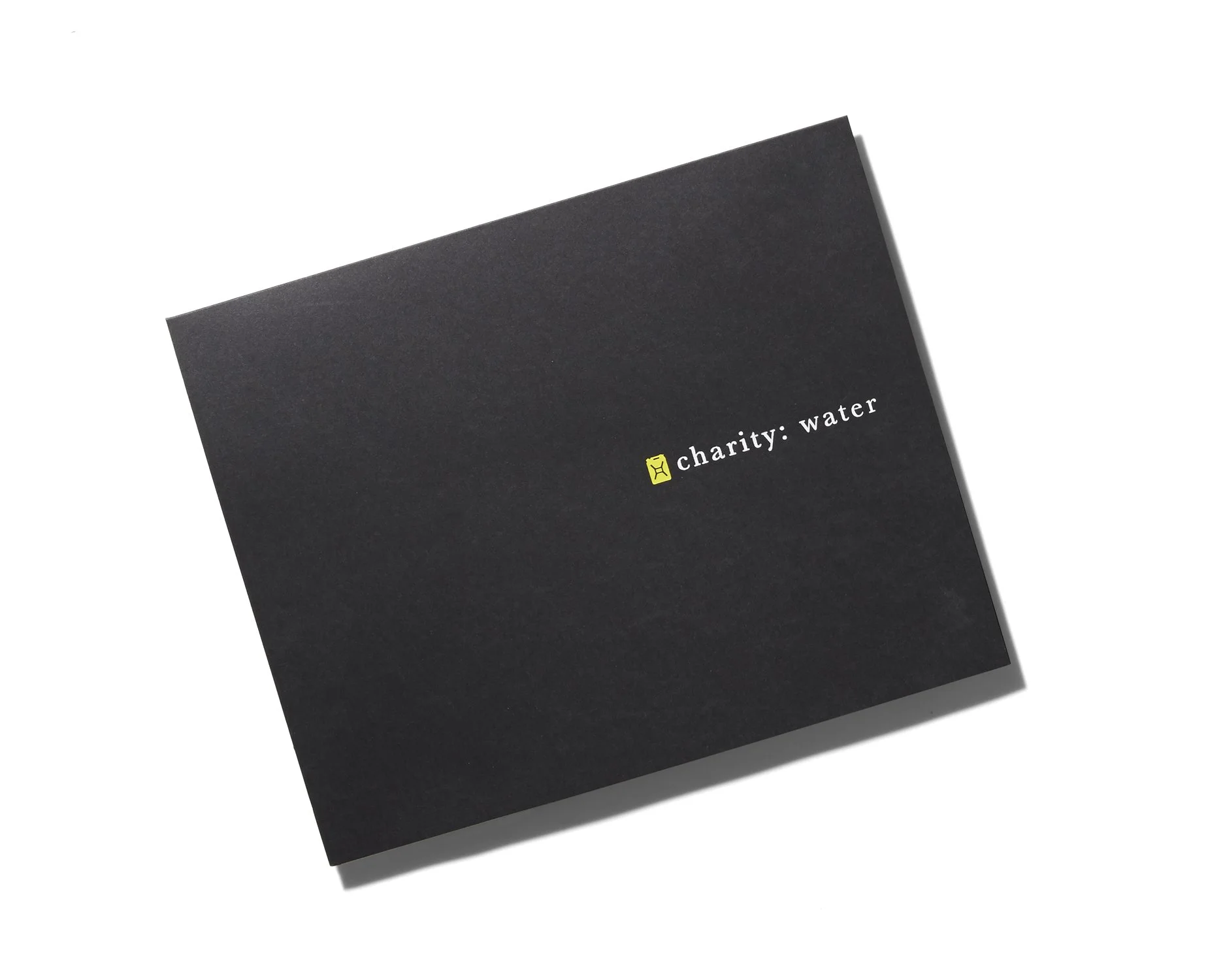 Black charity water donation box with white text and yellow logo.