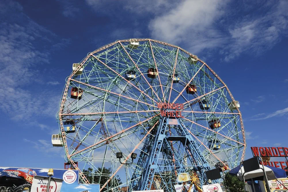 Large amusement park Ferris wheel named Wonder Wheel against a blue sky with clouds