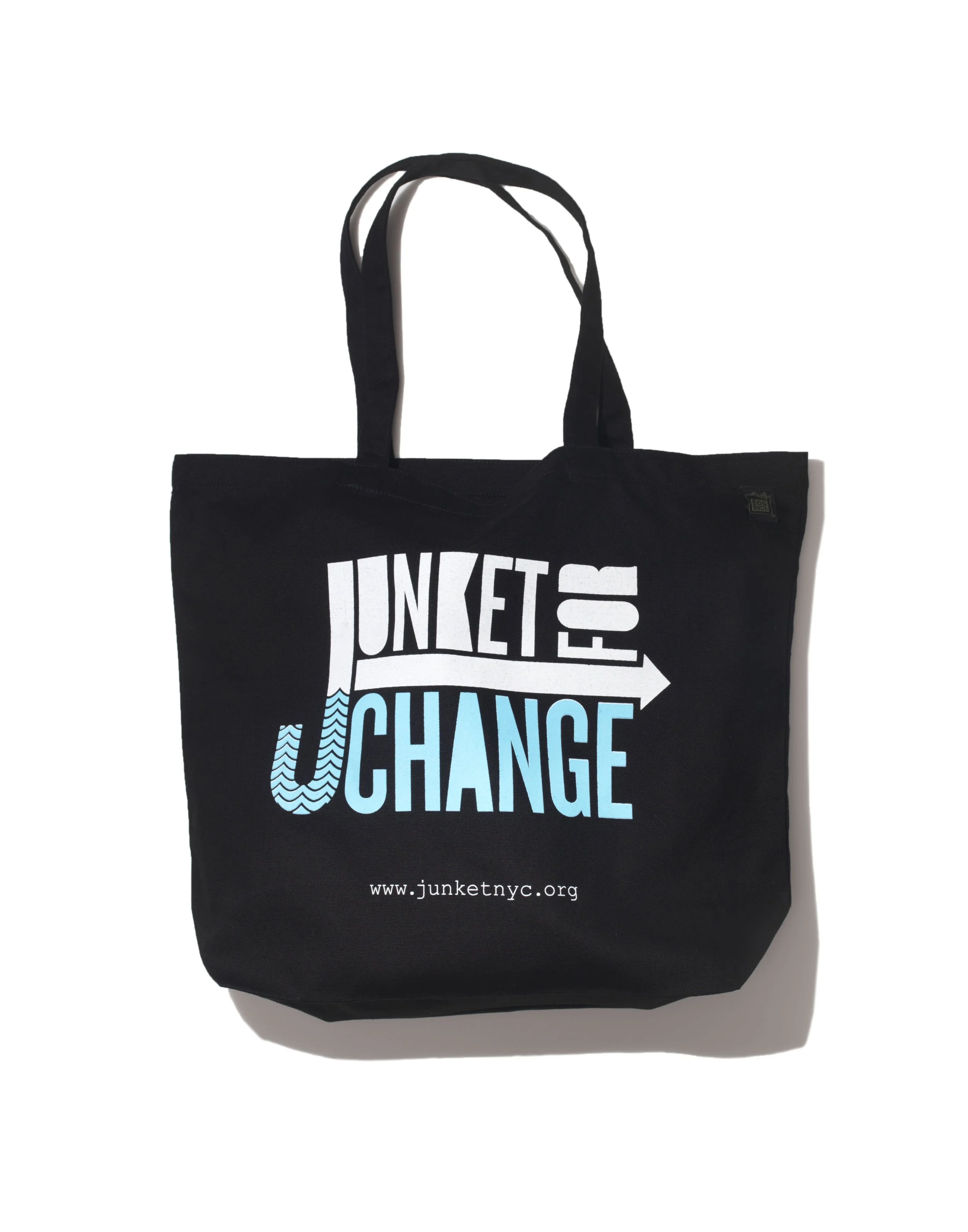 Black tote bag with the message "JUNKET IS OUR JCHANGE" in bold white and blue text, and a URL www.junketnyc.org at the bottom.