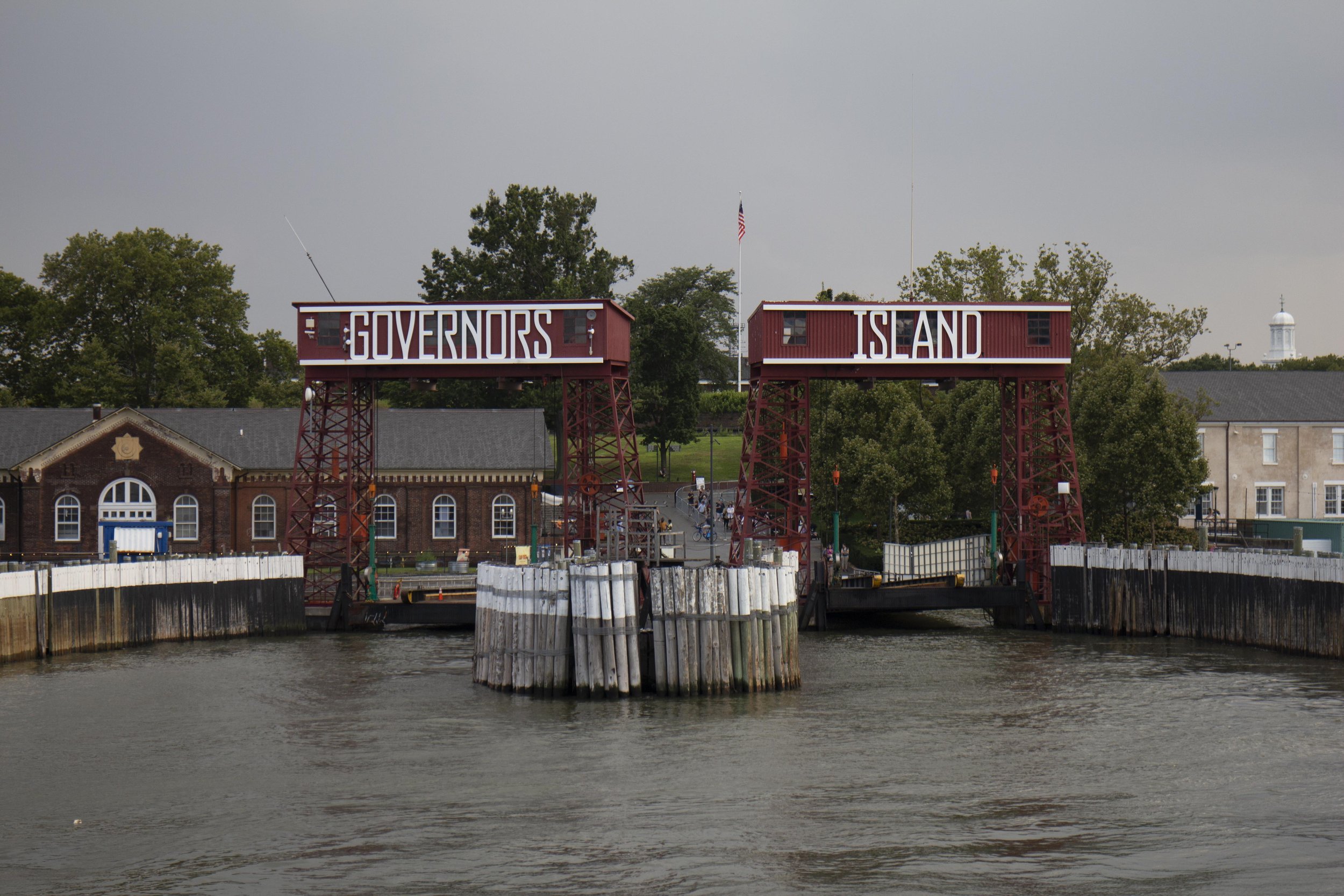 Waterfront gate with red metal structures, displaying the words 'Governors Island'.