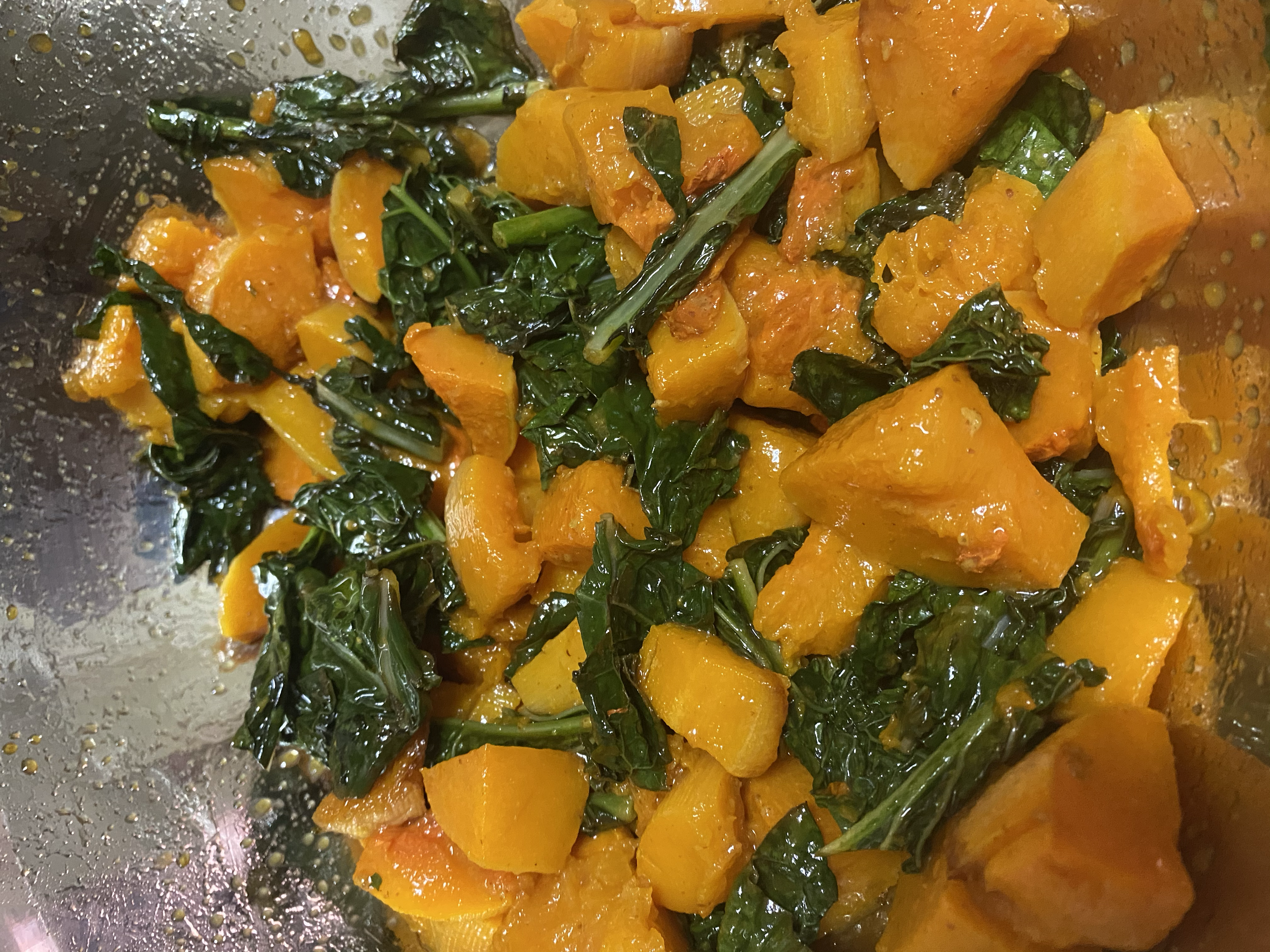 Cooked dish with chunks of roasted butternut squash and wilted kale.