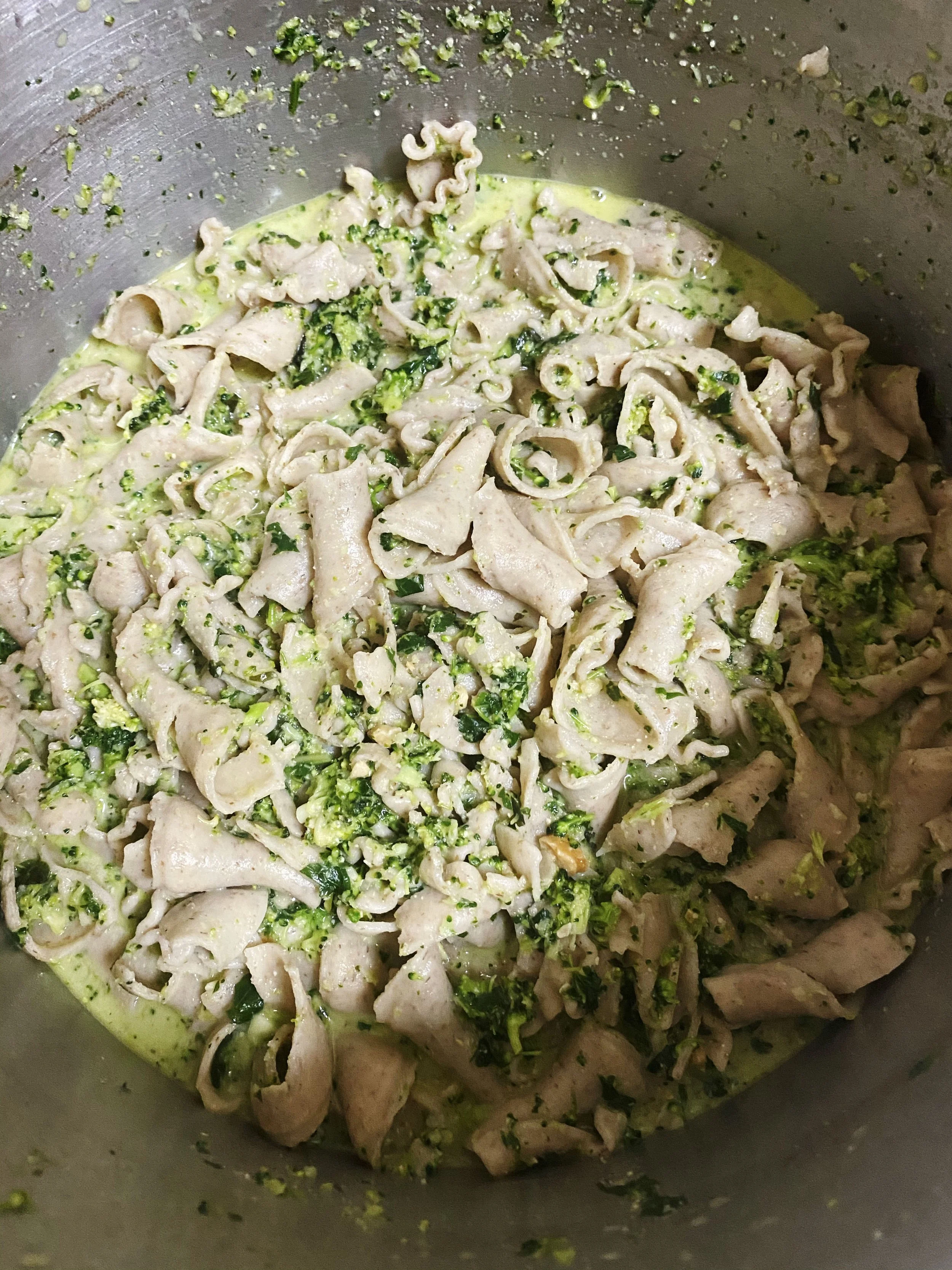 Cooked chicken and broccoli in a creamy sauce inside a large pot.