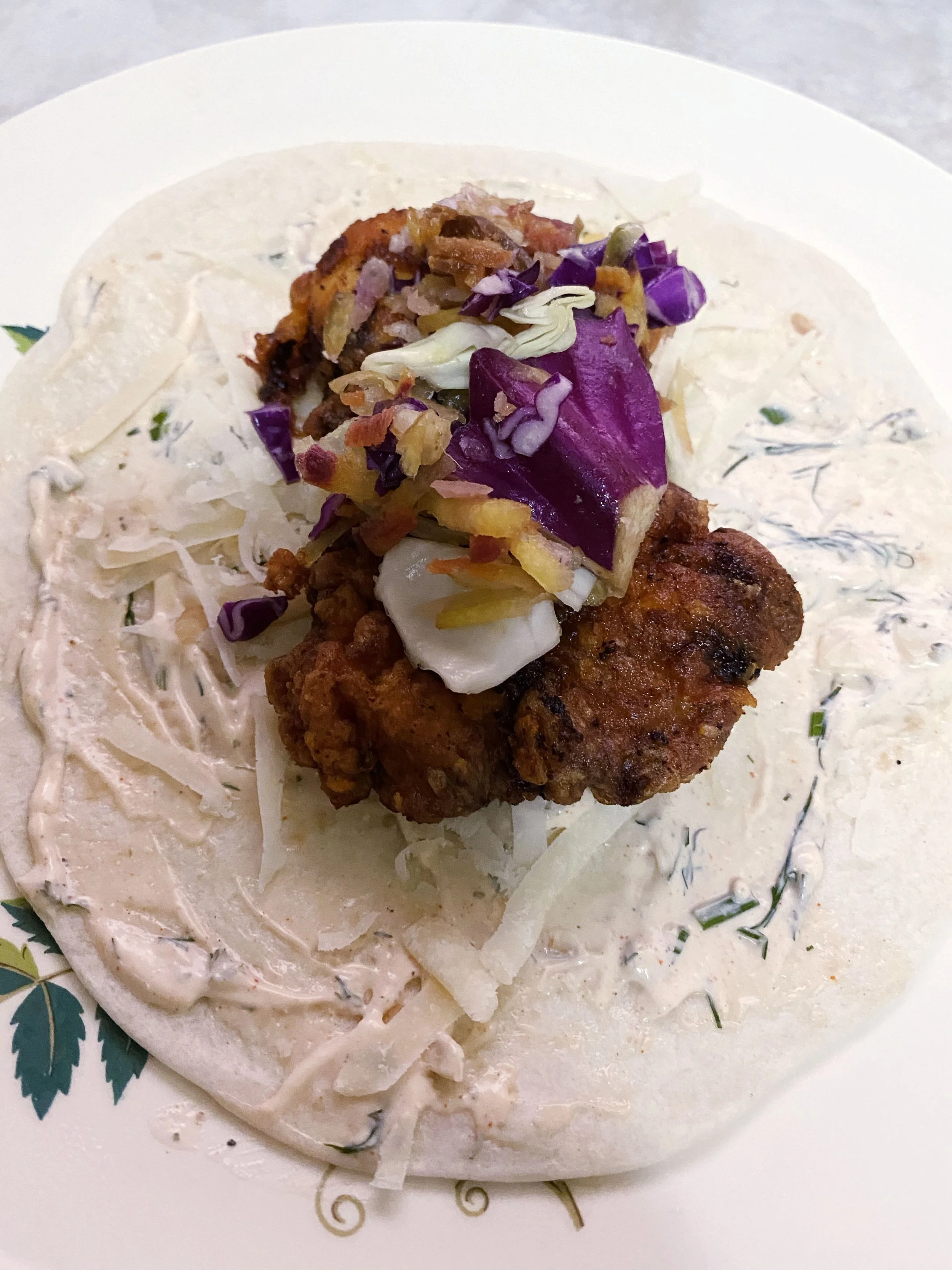 Fried chicken sandwich with coleslaw on a bun, served on a white plate.