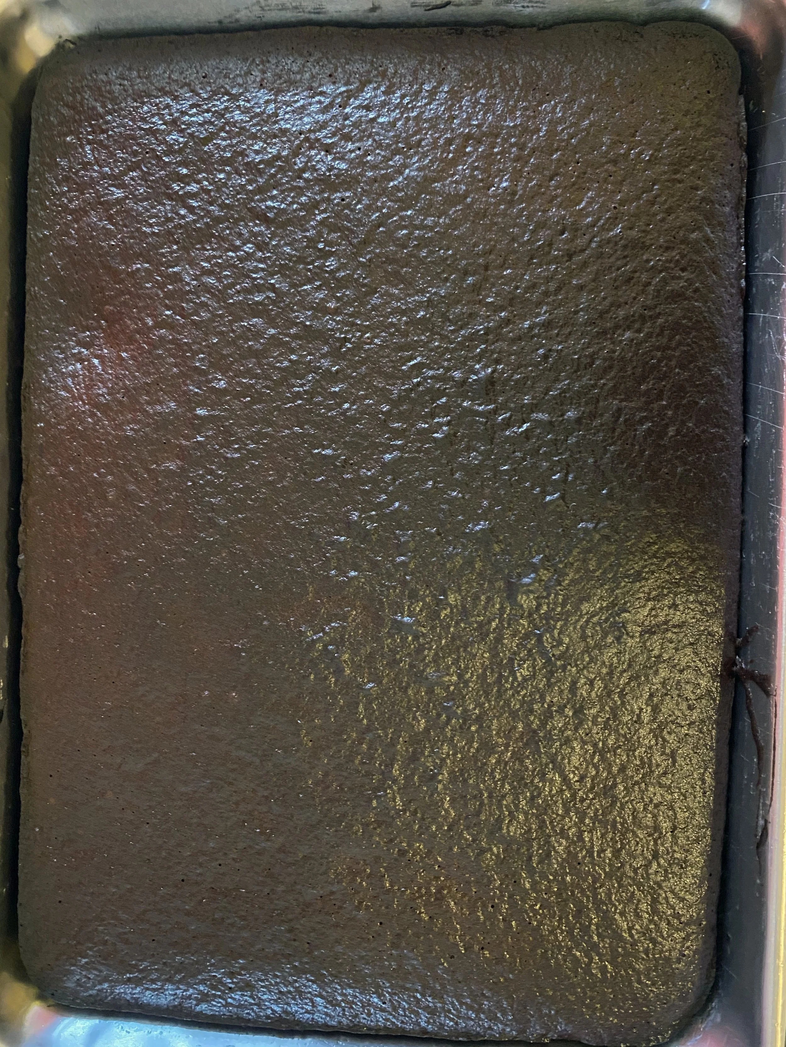 Close-up of a rectangular tray filled with smooth, dark chocolate cake batter.