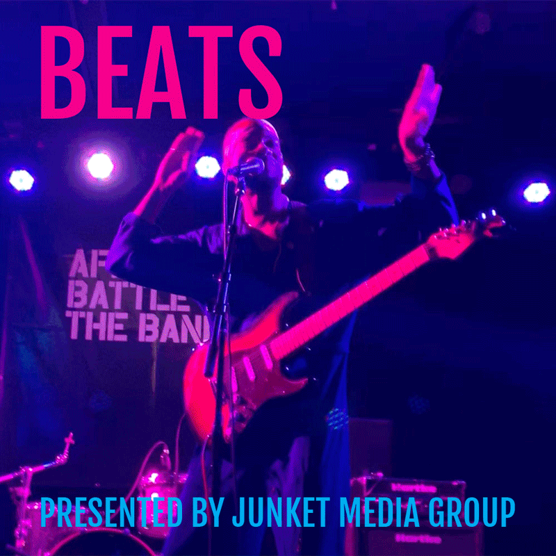 Musician on stage with guitar, singing into microphone with colorful stage lighting, large pink text 'BEATS', and blue text 'Presented by Junket Media Group'.