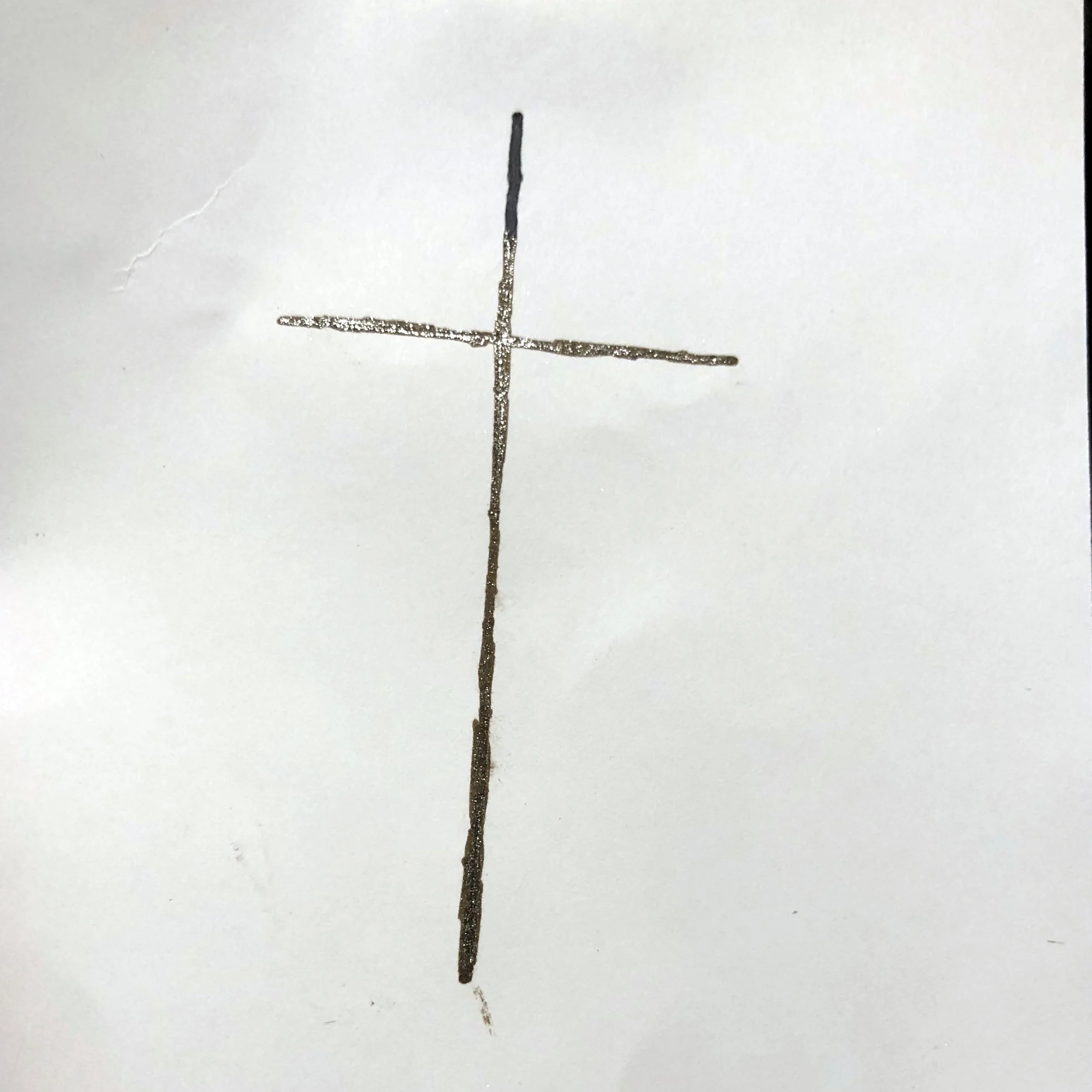 A simple black cross drawn on a white piece of paper.