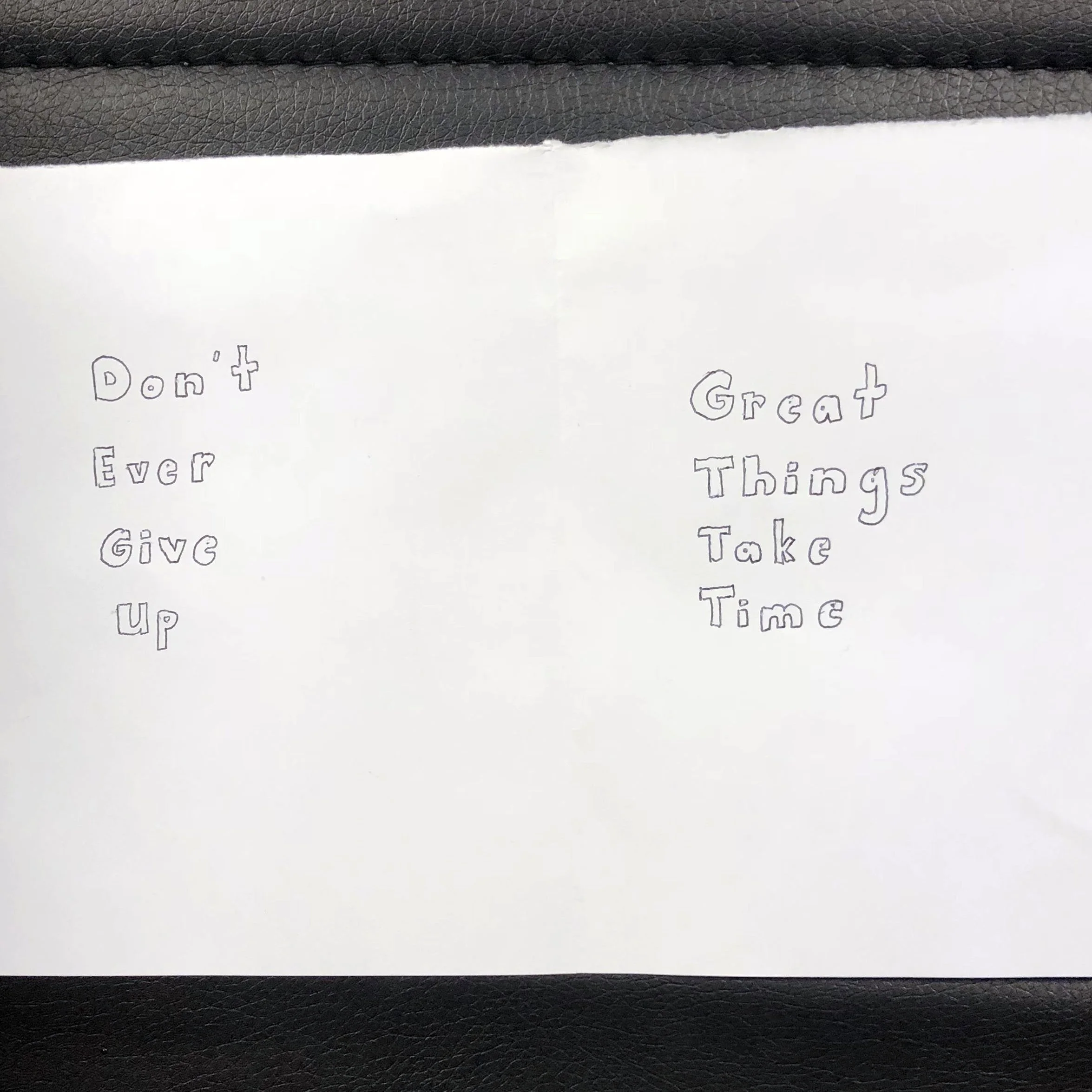 A handwritten note on white paper with a quote: 'Don't Ever Give Up' on the left side and 'Great Things Take Time' on the right side.