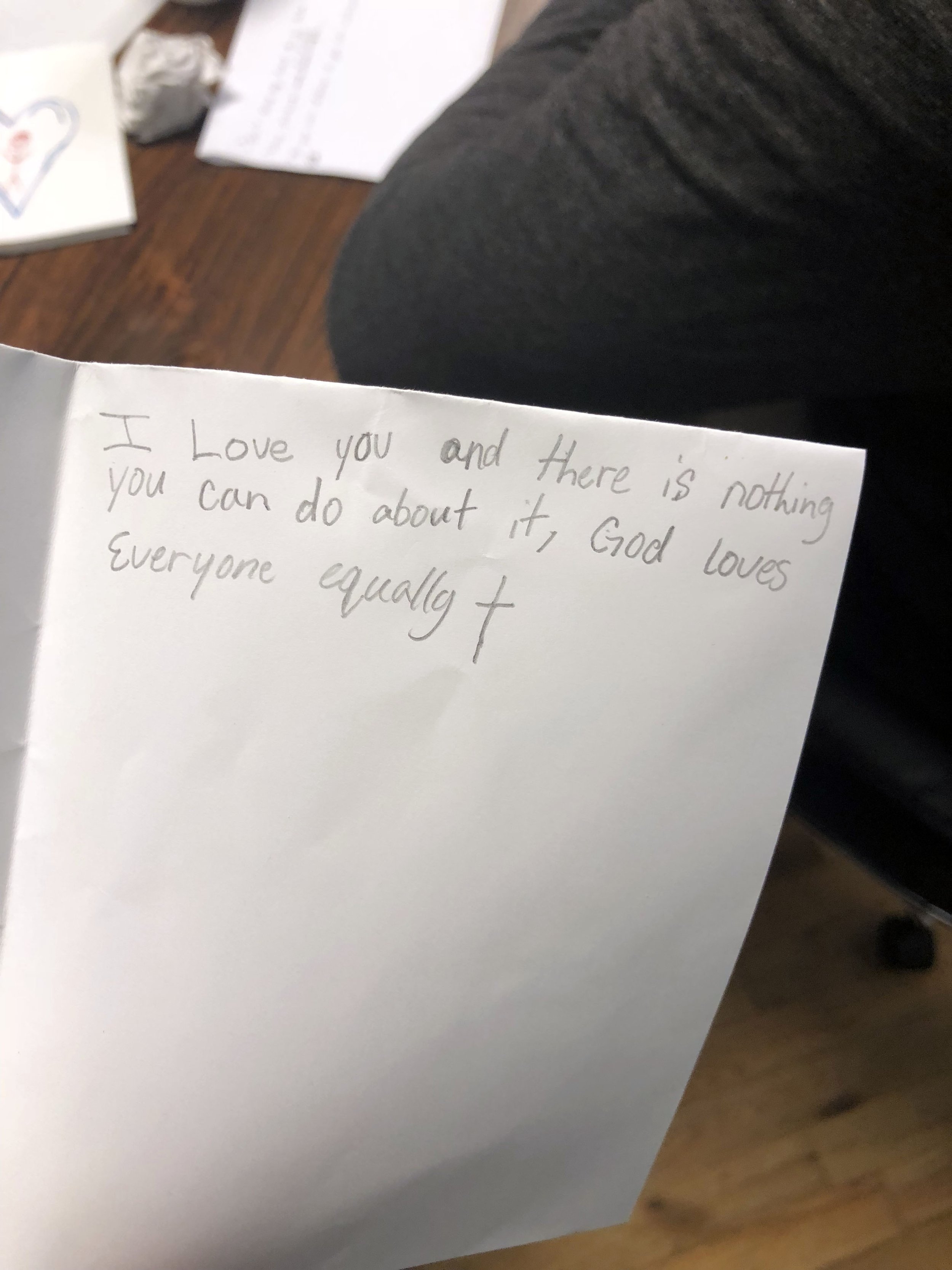 A handwritten note on a white piece of paper reading 'I Love you and there is nothing you can do about it, God loves everyone equally'.