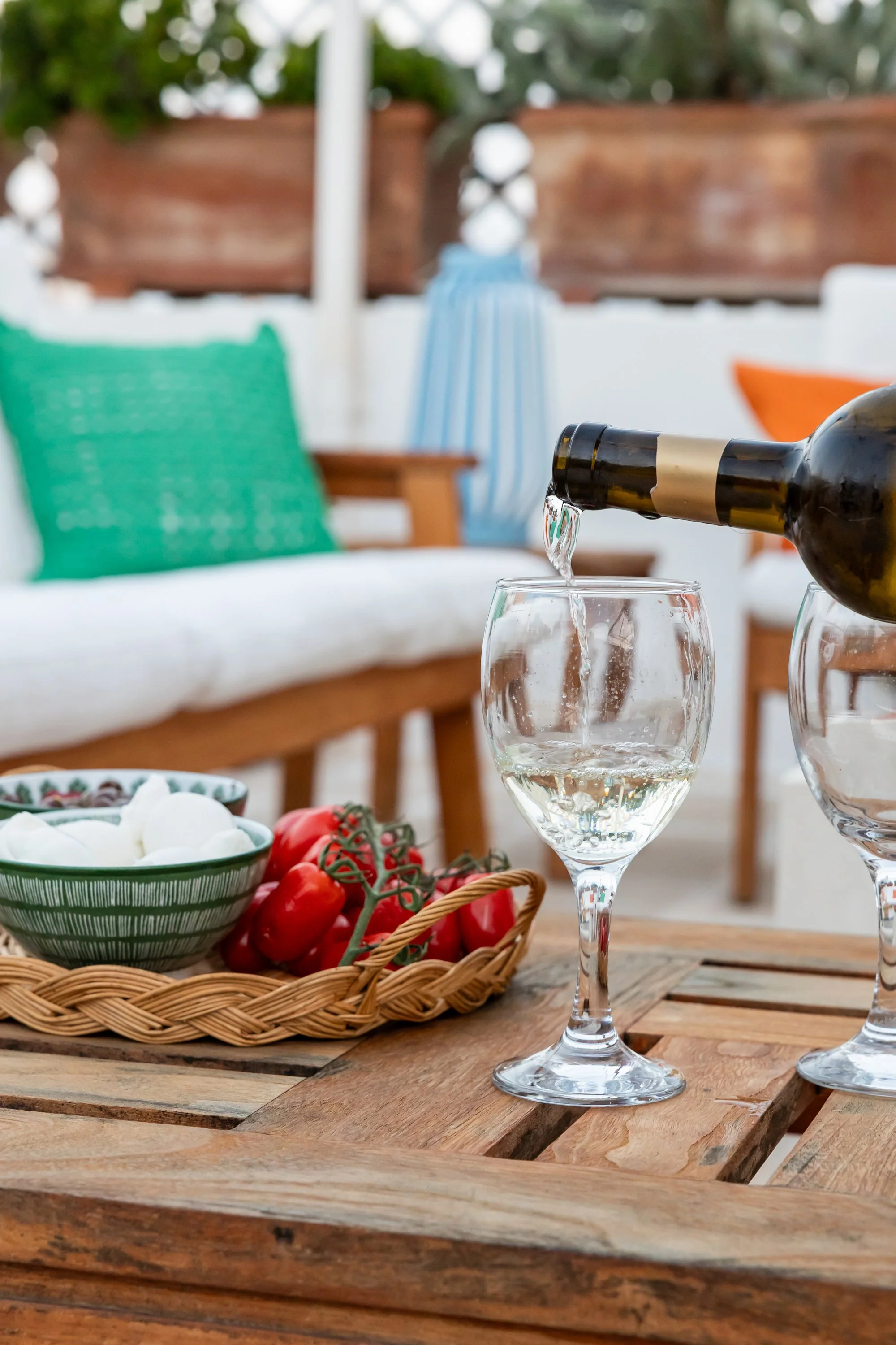 Aperitivo moment in the outdoor living area at Palazzo Dolce Vita, with white wine, tomatoes and cheese on a wooden table.
