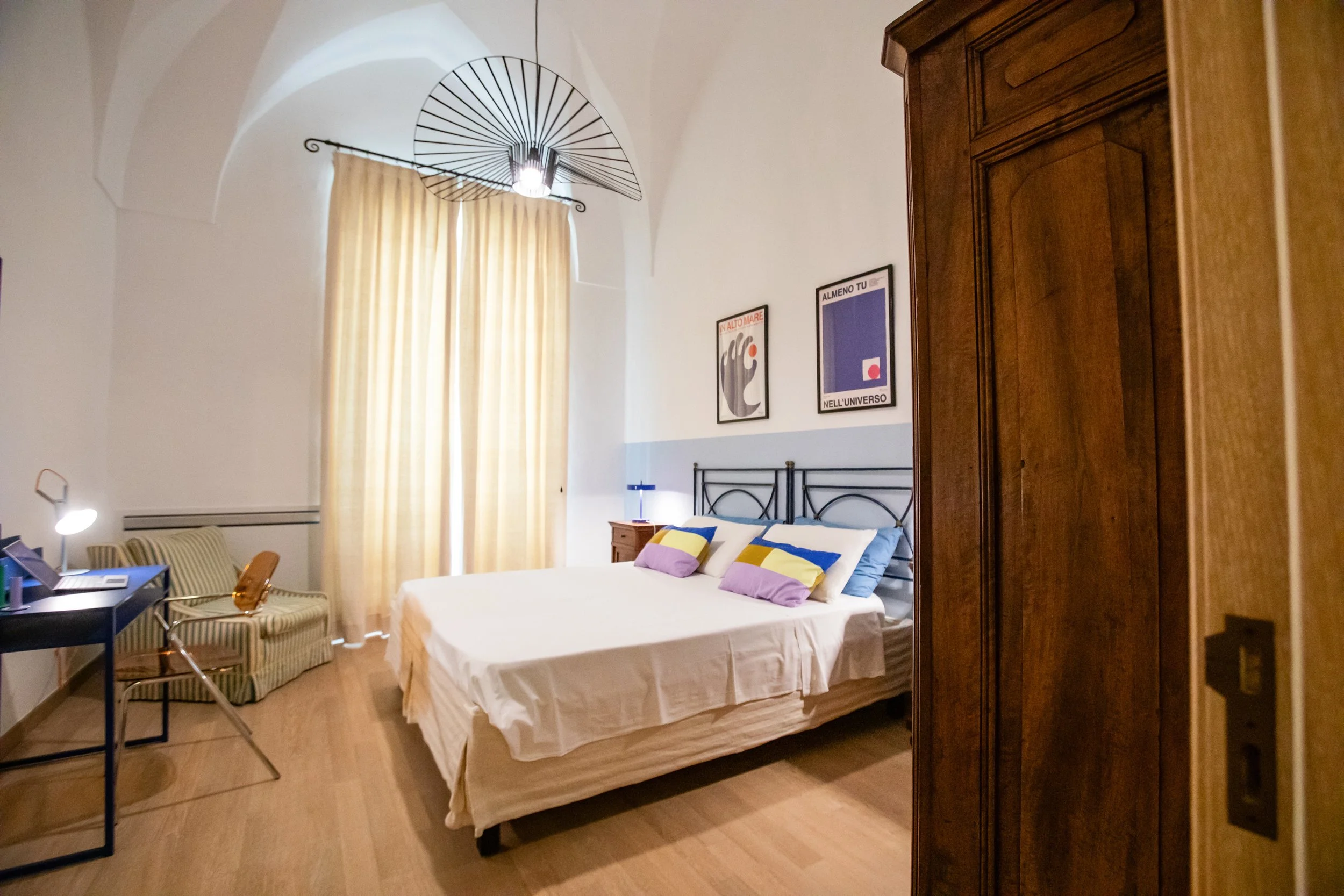 Double bedroom at Palazzo Dolce Vita with a dedicated desk for remote working, featuring high ceilings, wooden floors and curated artwork..
