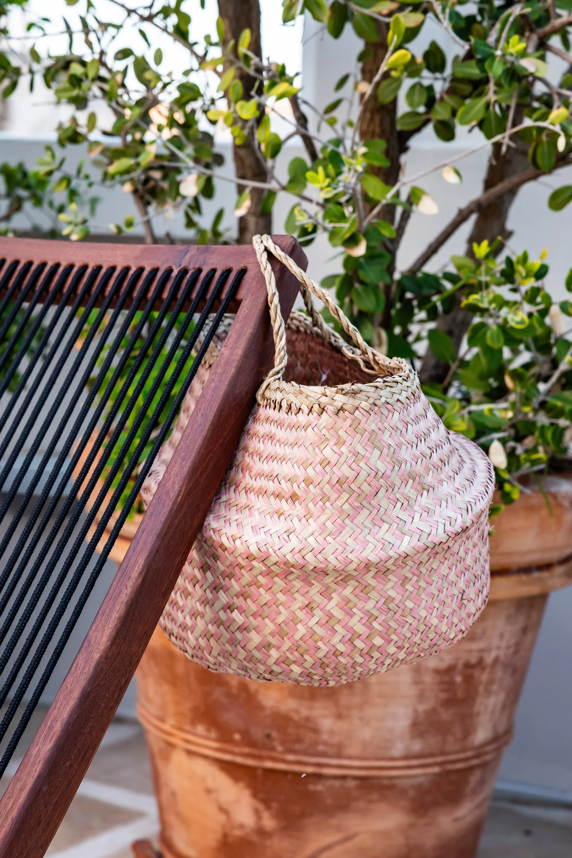 Relax corner on the terrace at Palazzo Dolce Vita, with natural textures, a woven bag and Mediterranean greenery.