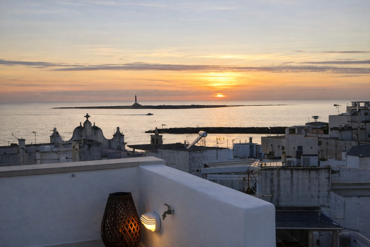 Sunset view from the rooftop of Palazzo Dolce Vita, with the lighthouse of Isola di Sant’Andrea on the horizon.