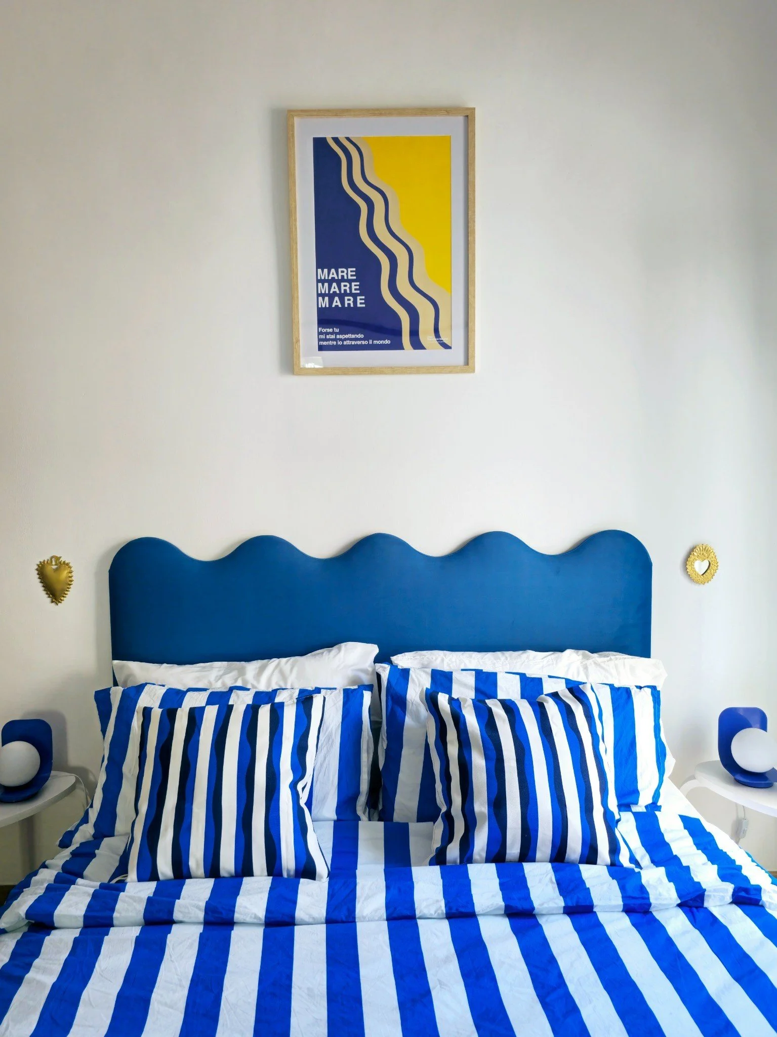 Double bedroom with private balcony at Palazzo Dolce Vita, styled with blue and white tones, striped bedding and curated artwork.