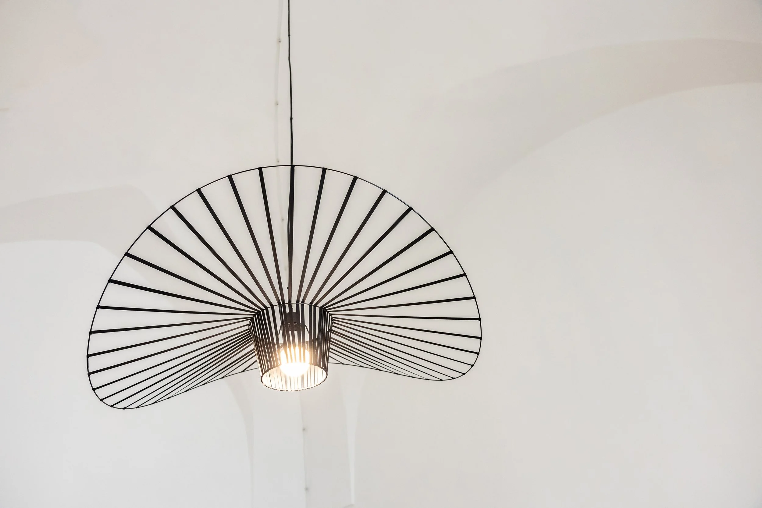 Modern black metal pendant light fixture with a circular, open design hanging from a white ceiling.