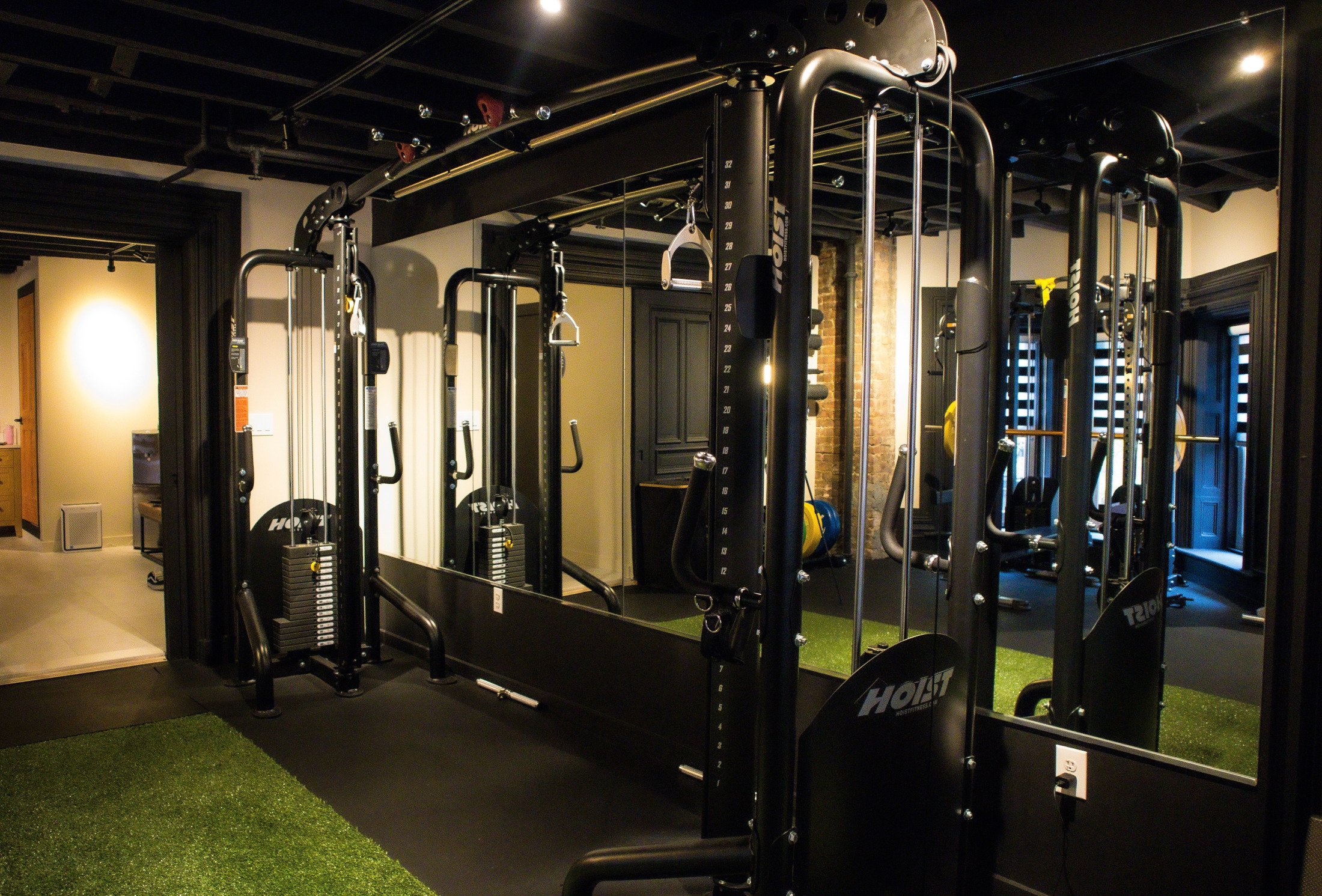 Gym with black workout equipment, mirrors, and 30ft turf.