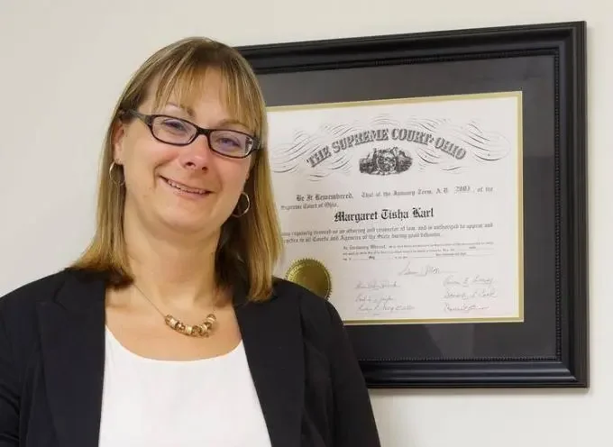 Attorney Margaret T. Karl standing beside her Ohio Supreme Court admission certificate in professional attire