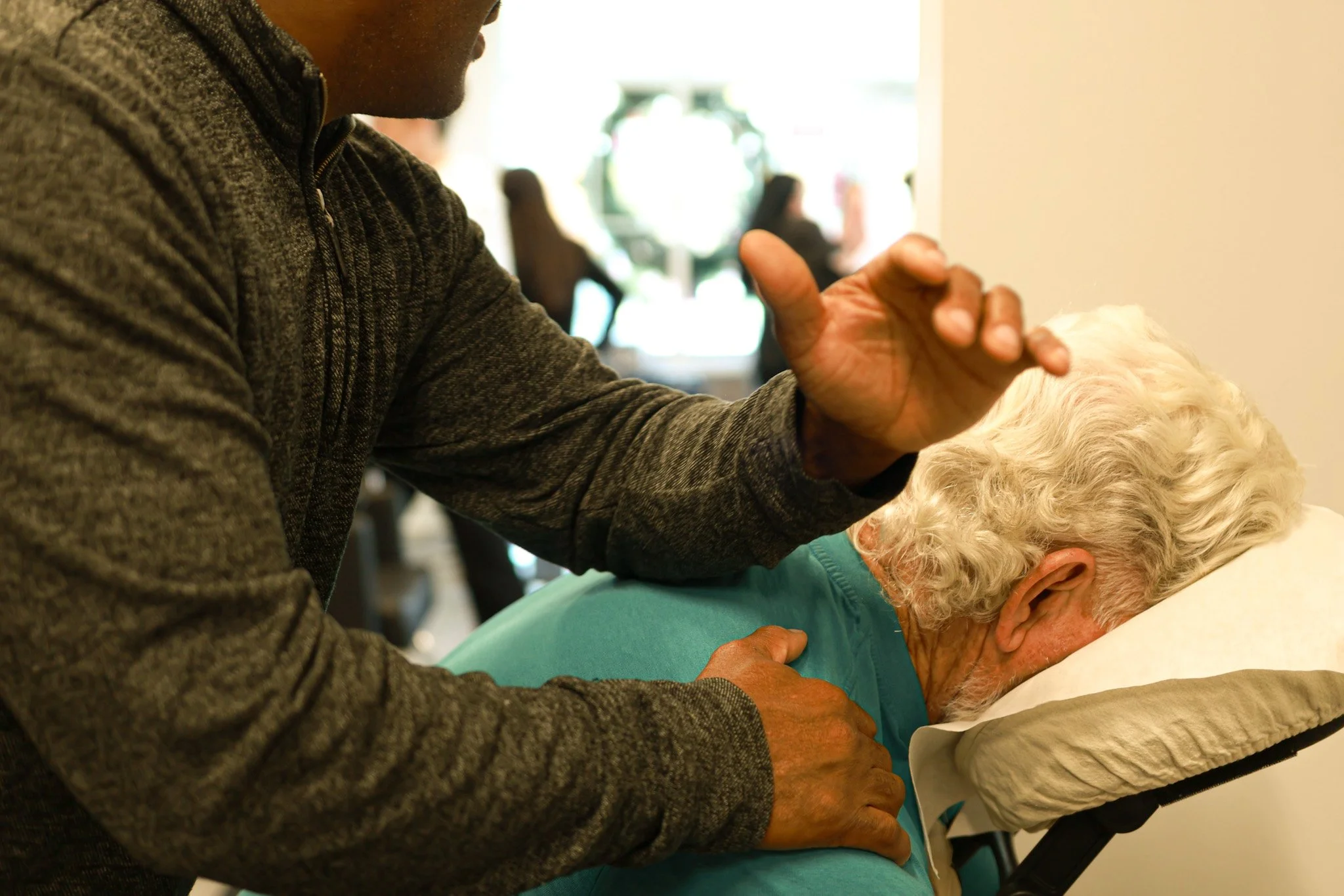 A man performing CPR on an elderly woman lying on a hospital bed.