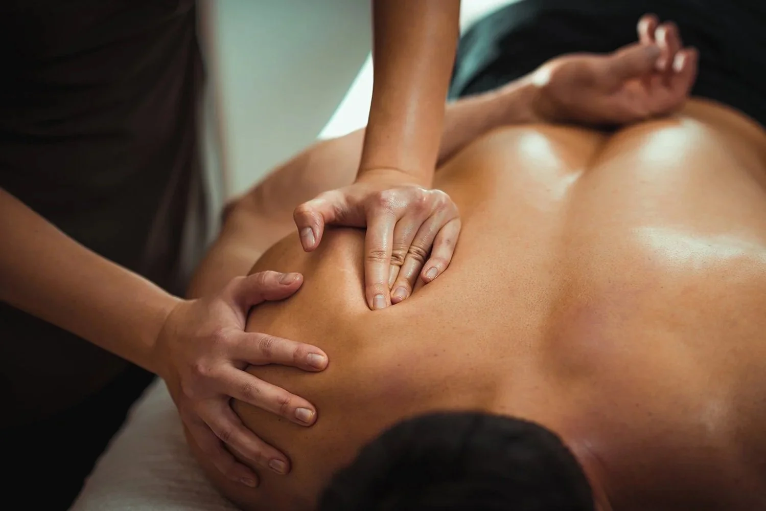 A person receiving a massage on their back from a massage therapist.