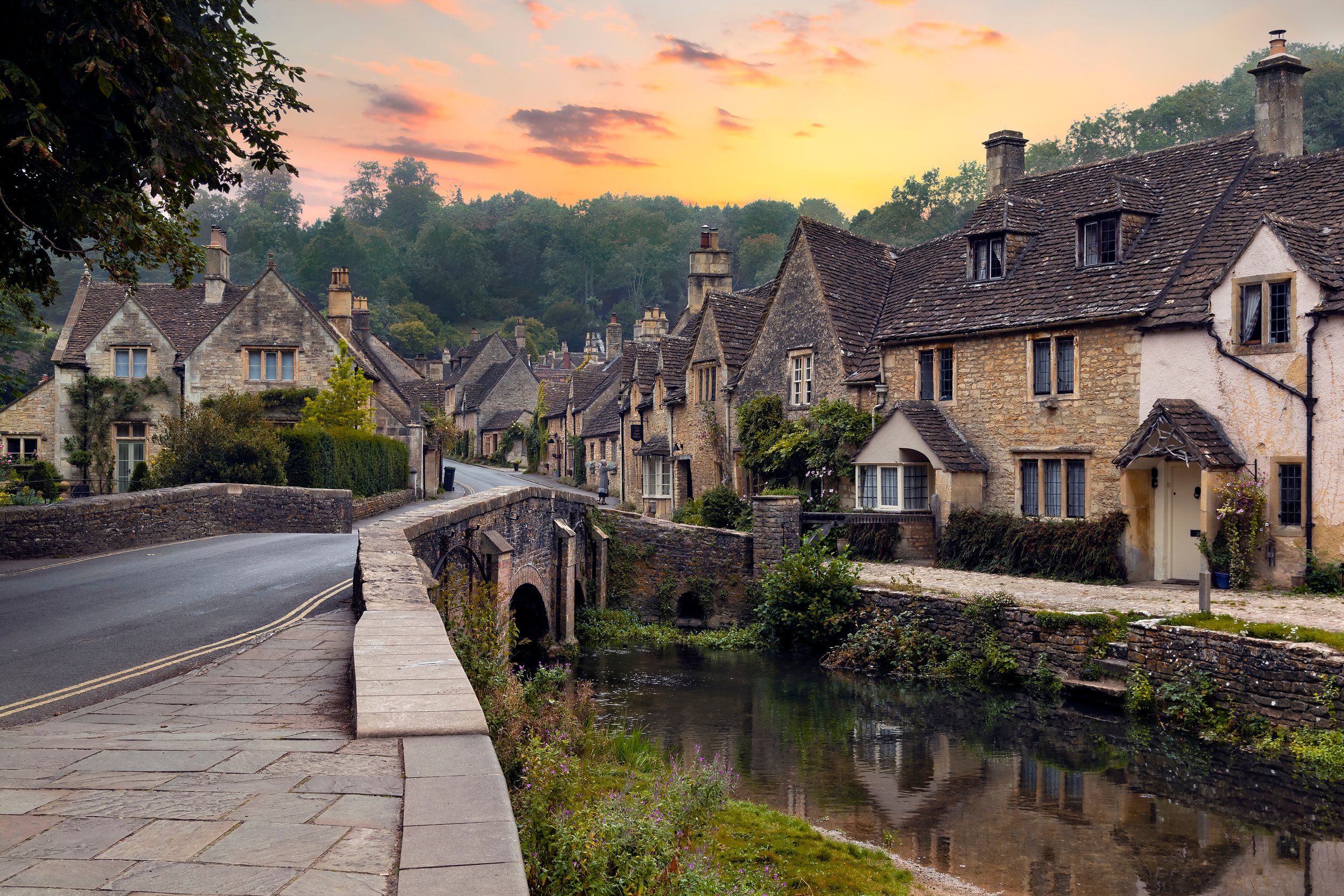 Cotswolds village Castle Combe showing bridge and houses along main street.