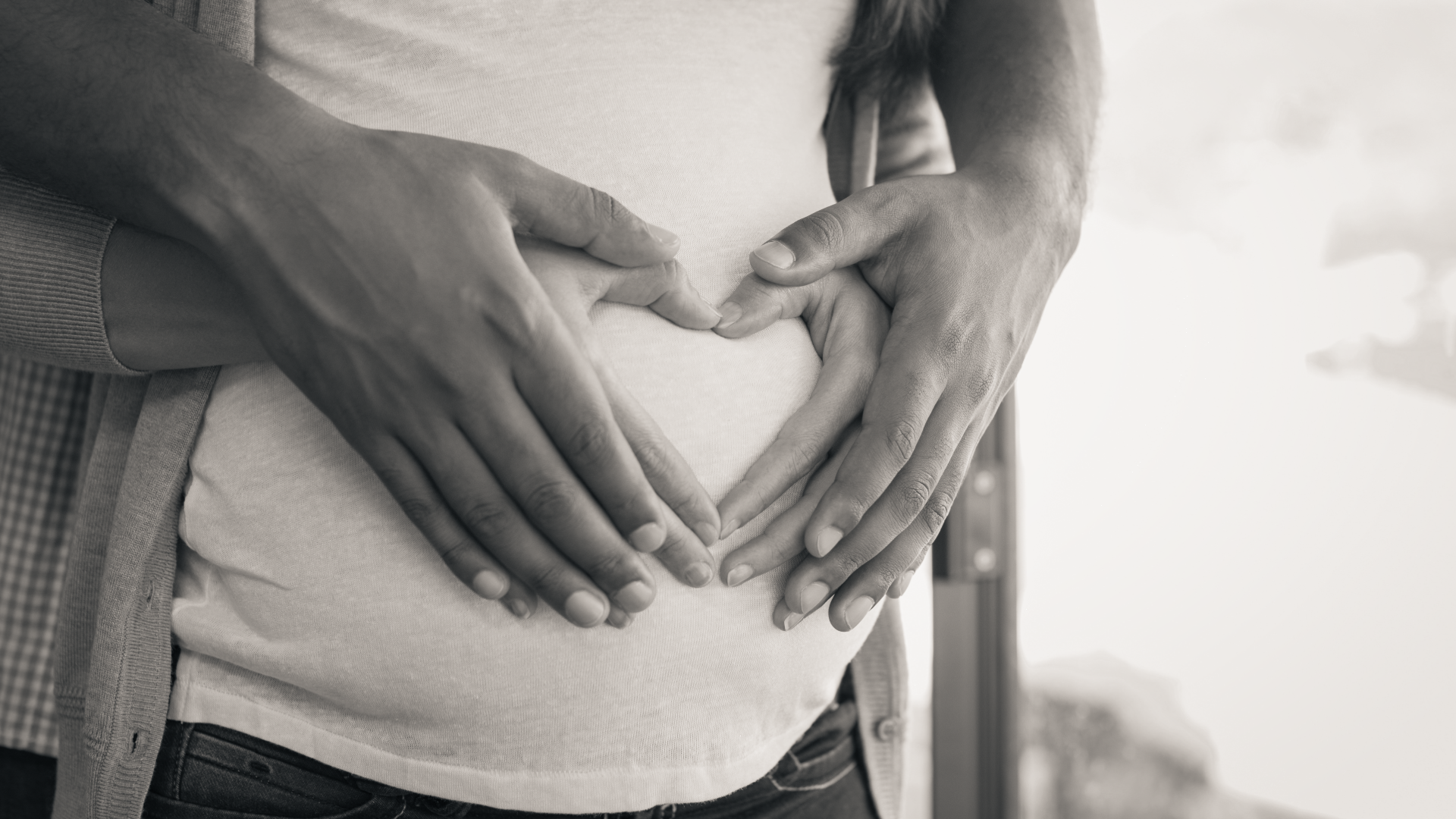 Parents hands overlapped holding pregnancy bump