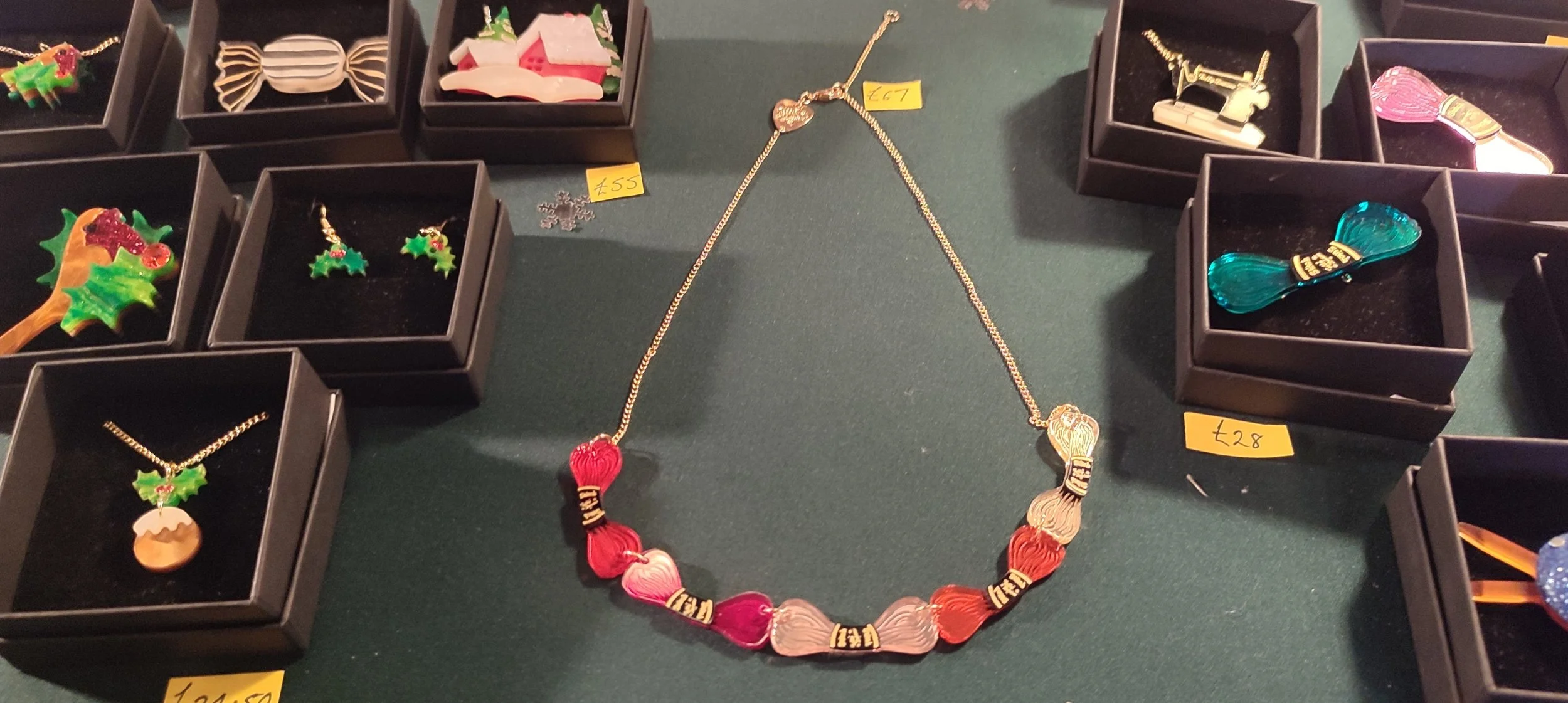 Colorful jewelry displayed on a table with some necklaces and earrings, including a multicolored heart-shaped necklace and holiday-themed earrings.