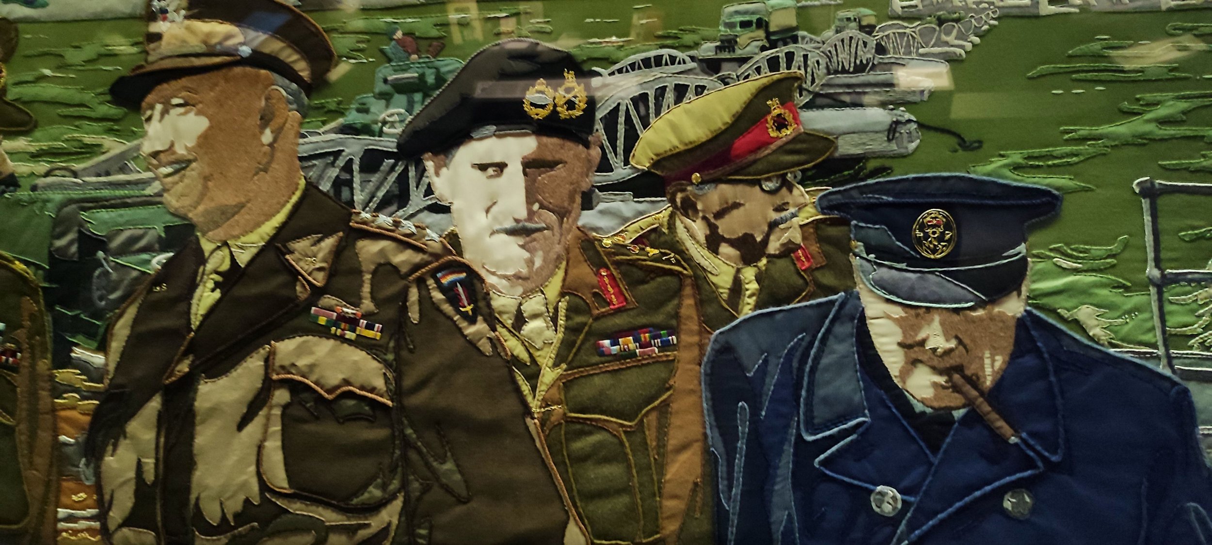 Fabric embroidery artwork of four military officers in uniform with medals, set against green background with tank and artillery motifs.