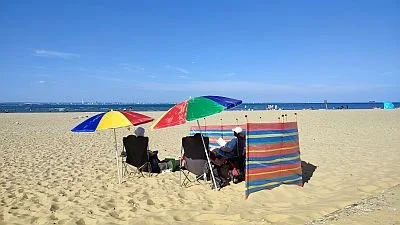 Beach scene with umbrellas, beach chairs, and people relaxing on the sand near the ocean