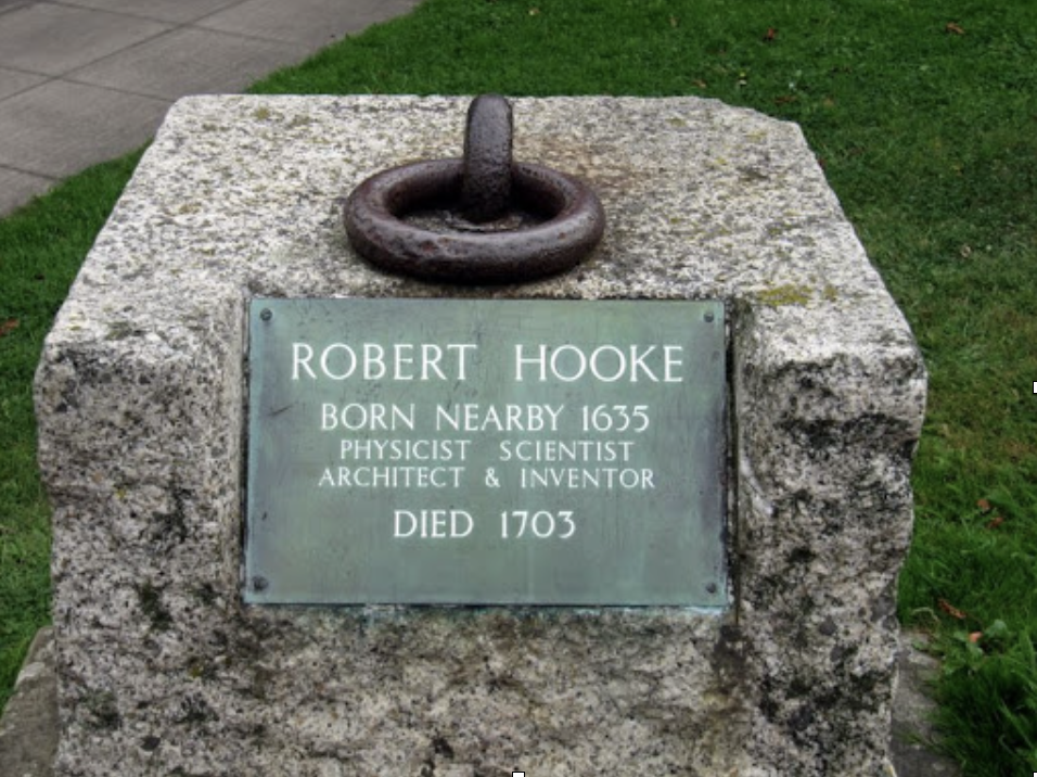 A stone monument with a metal plaque and an iron ring on top, dedicated to Robert Hooke, indicating he was born nearby in 1635, was a physicist, scientist, architect, and inventor, and died in 1703.