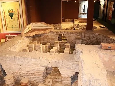 Excavated archaeological site with brick and stone ruins inside a building.