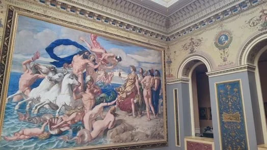 A large classical style painting depicting mythological figures on a wall in a decorated room with ornate architectural details and a gold-accented blue door.