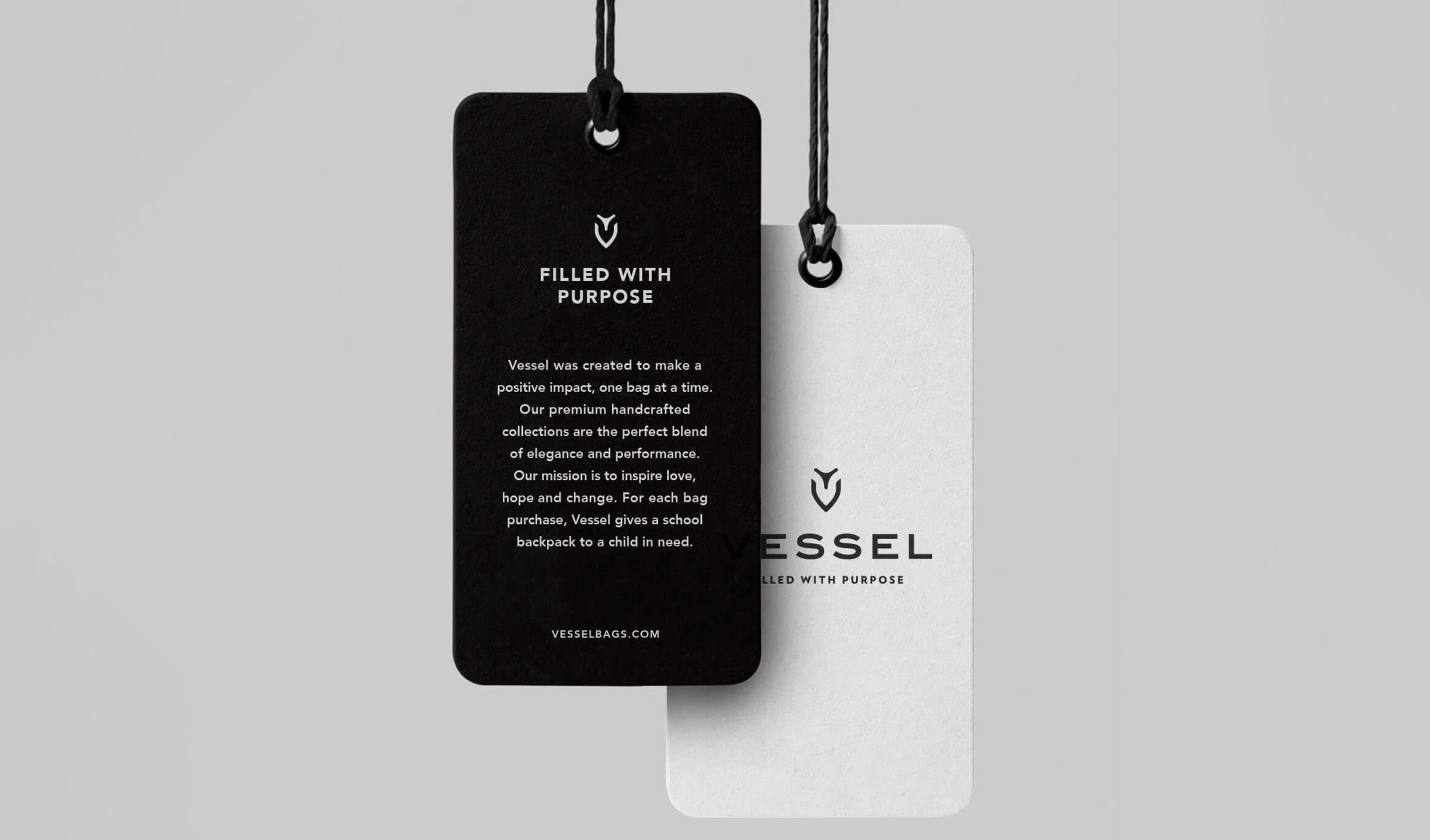 Two tags hanging on black string, one black with white text and one white with black text. The black tag reads 'Filled with Purpose', and the white tag reads 'Vessel' with a logo above it.
