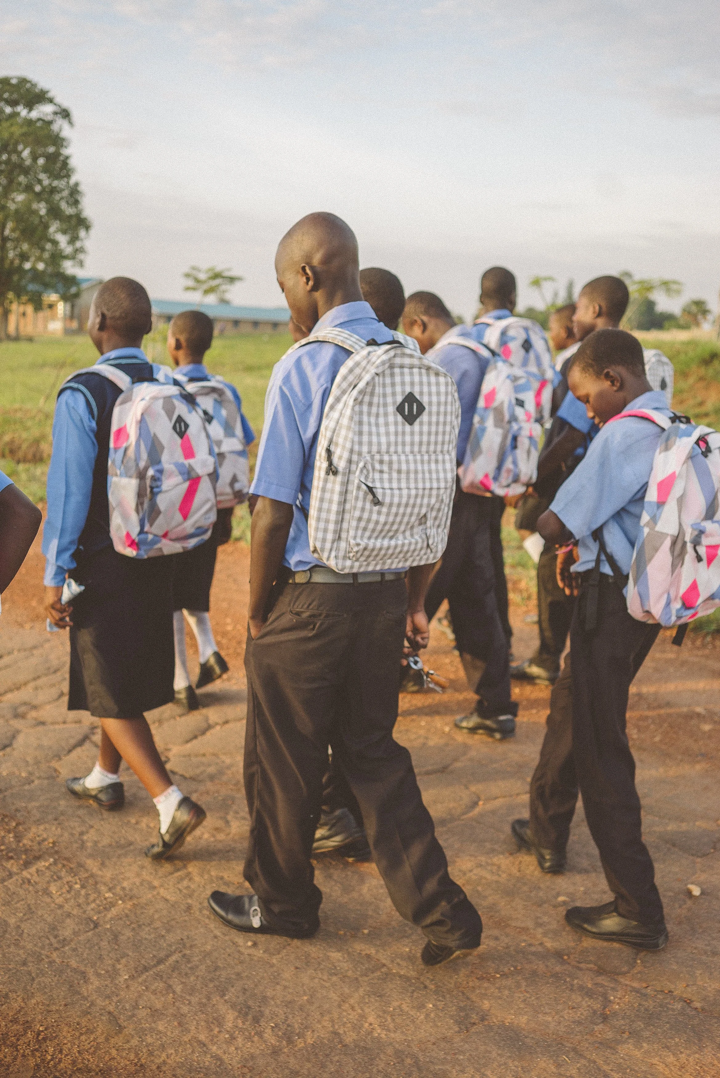 School children in uniform walking together outdoors with backpacks.