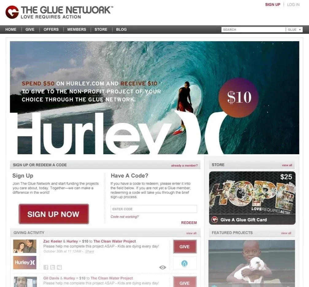 Screenshot of The Glue Network website featuring a large surfing image with a surfer on a wave, promotional message about spending $50 at Hurley.com to give $10 to a non-profit project, a sign-up button, a section for redeeming codes, a store ad for a $25 gift card, and featured project images including children with puppies.