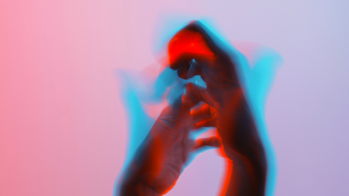 A hand holding a small object, with colorful light effects creating a vibrant, abstract atmosphere.