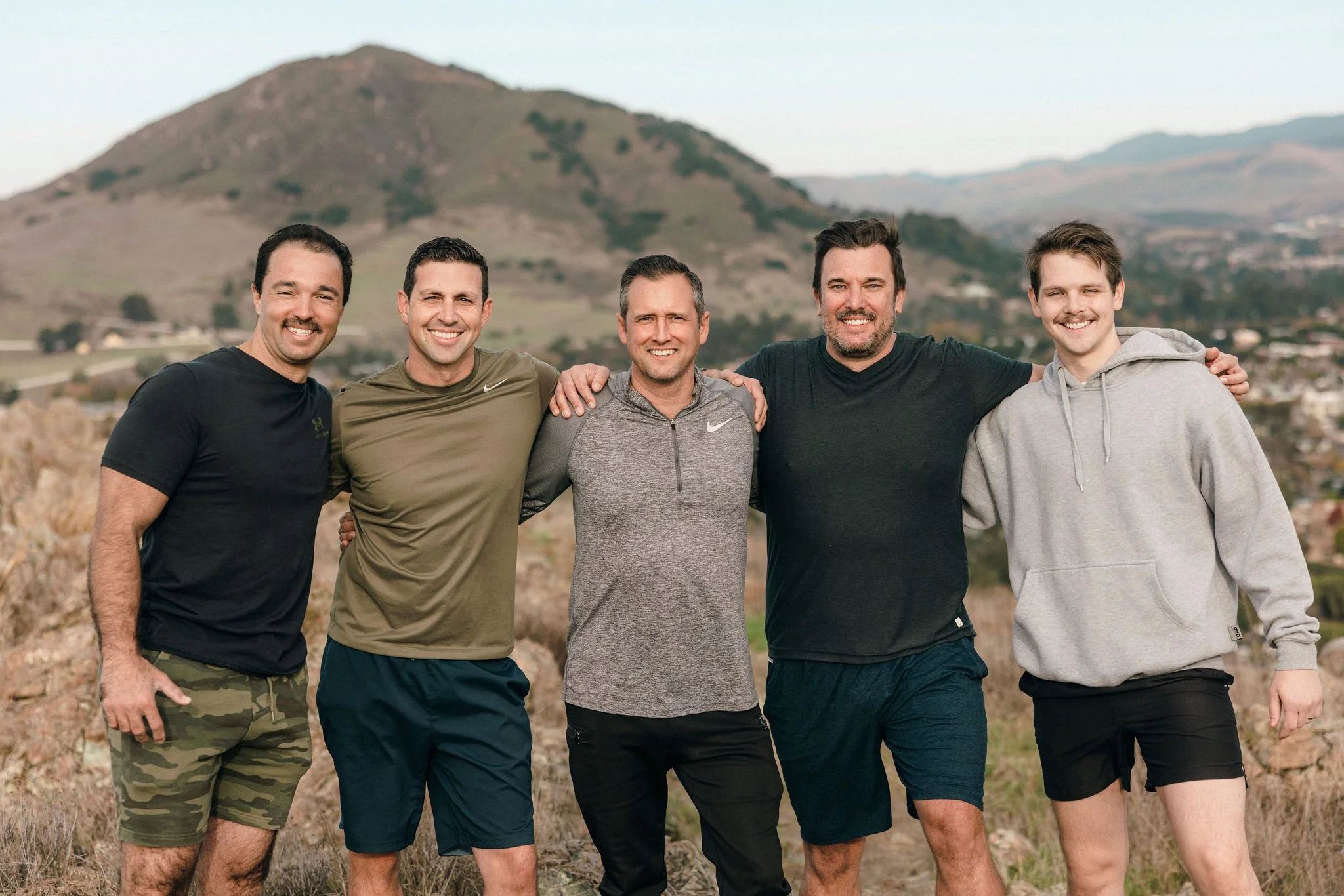 Group of five men standing together outdoors representing brotherhood and shared commitment in 100xLife.