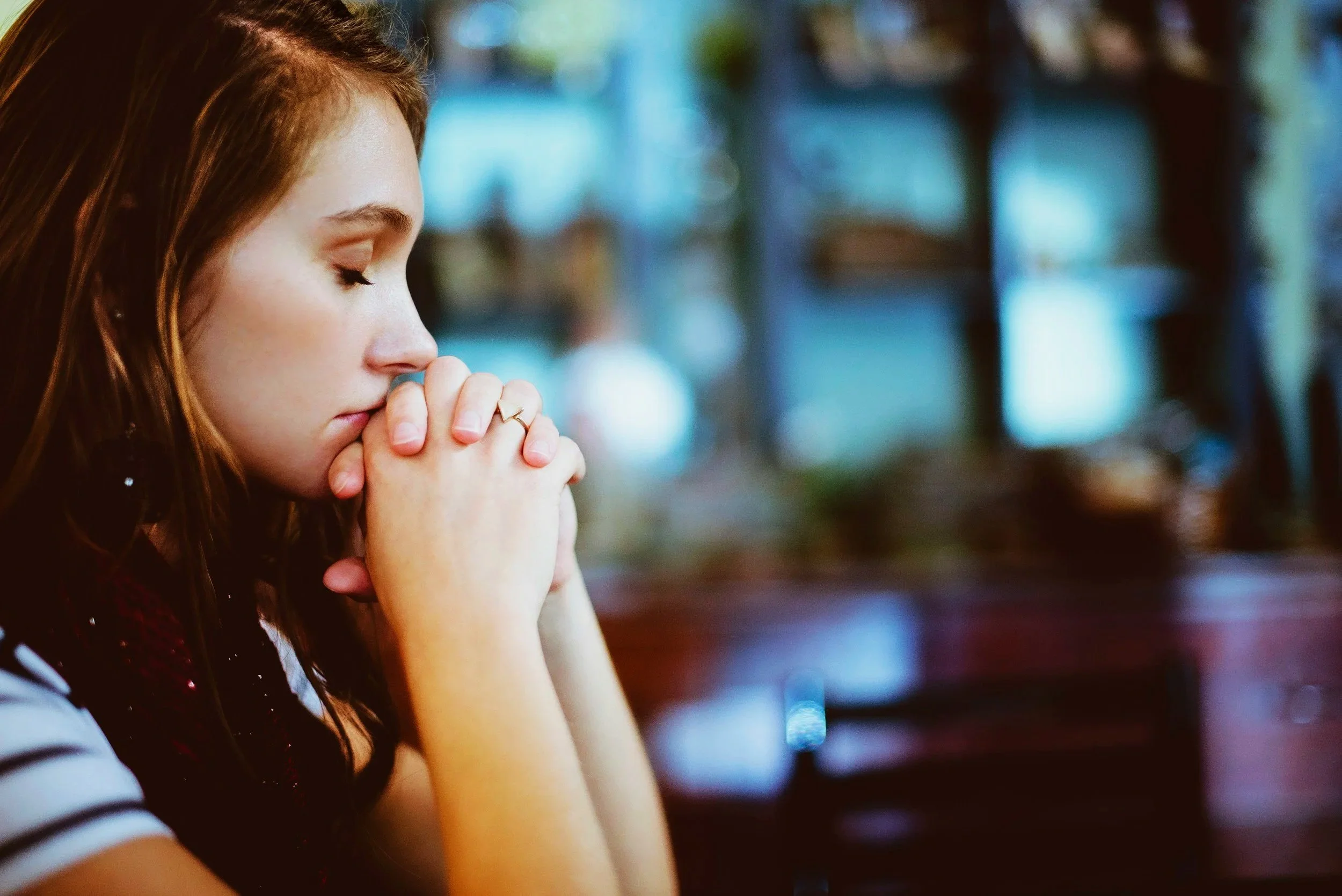 Woman praying with hands clasped as part of a daily Scripture-based practice.