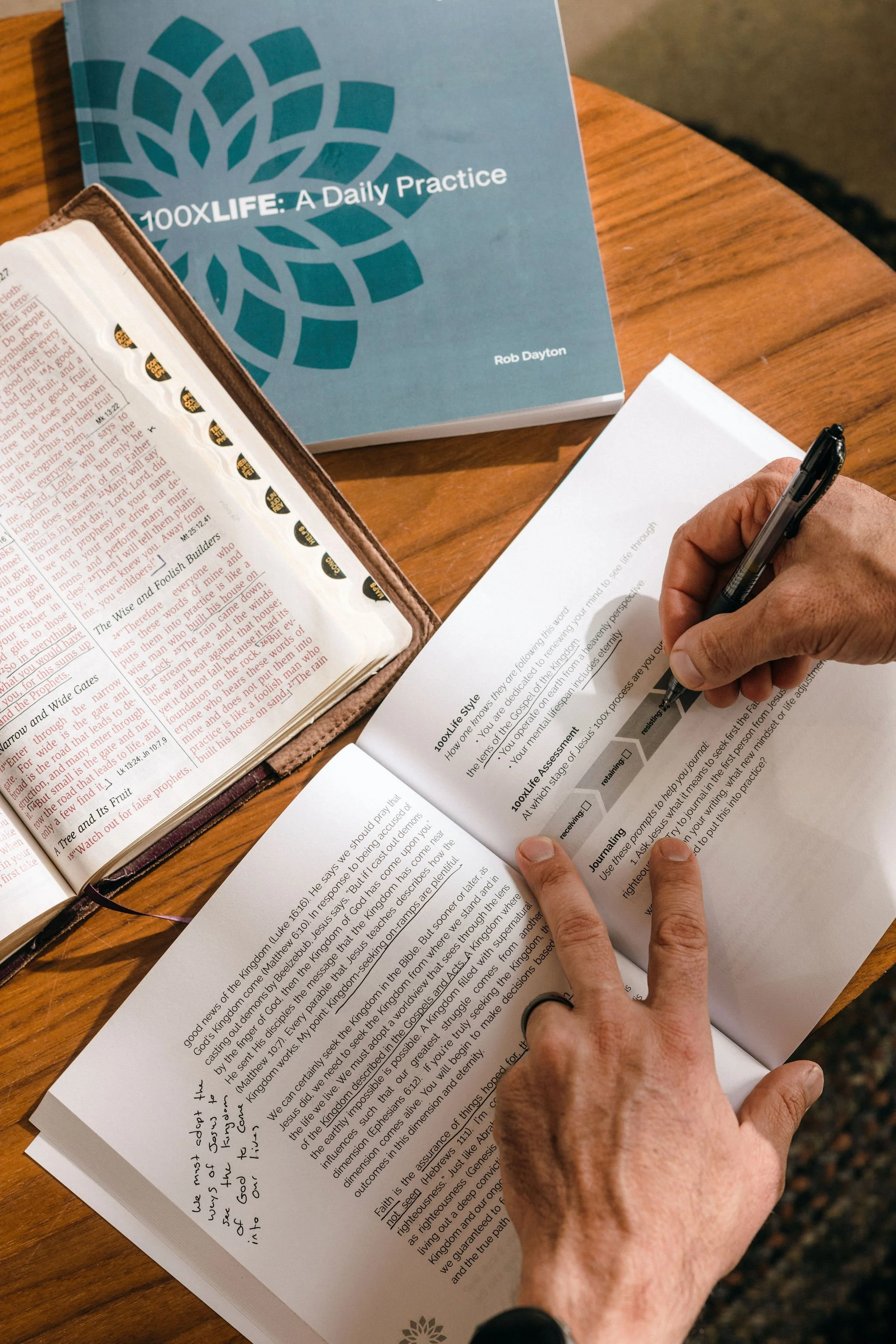 Person journaling and completing reflections as part of the '100XLife: A Daily Practice' by Rob Dayton.
