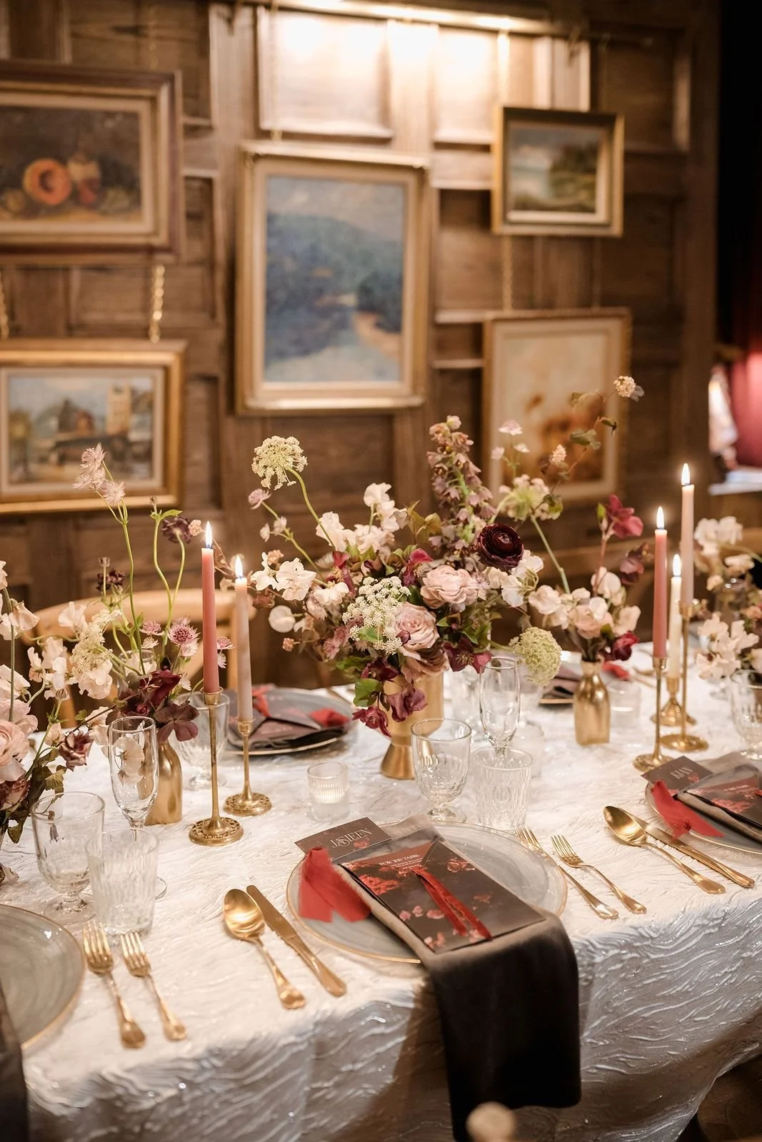 Elegant wedding reception table with romantic floral arrangements, taper candles, gold flatware, and vintage decor.