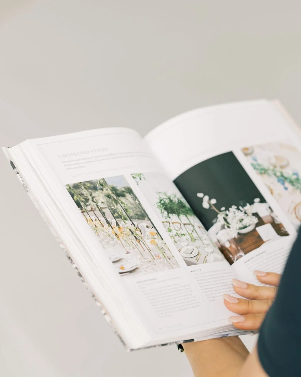 Person holding an open magazine featuring interior and design ideas with flower arrangements.
