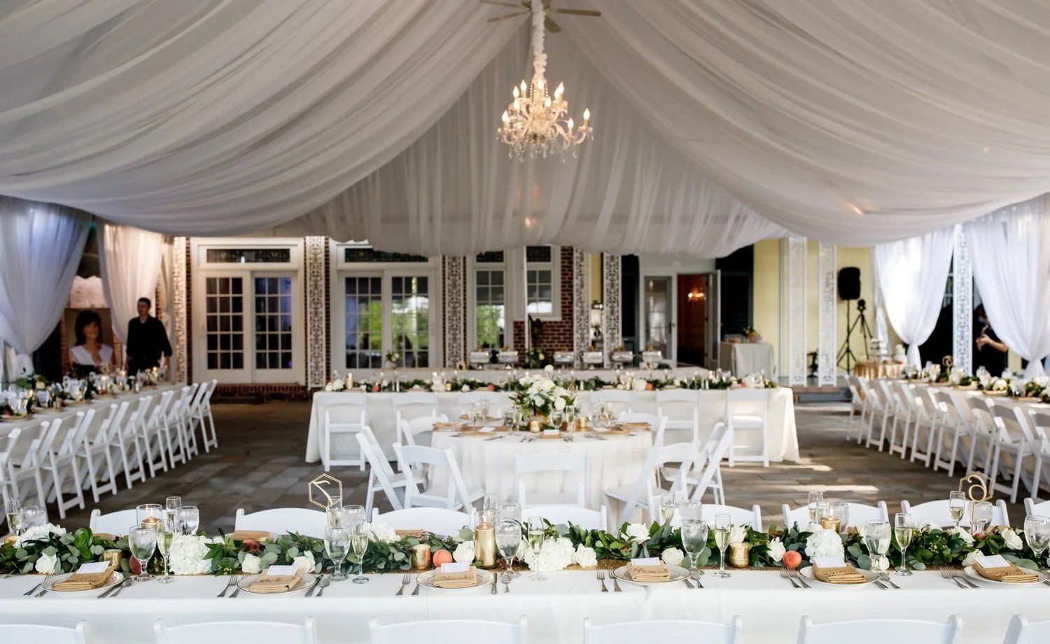 hudson valley wedding tent reception layout with draped ceiling and chandelier