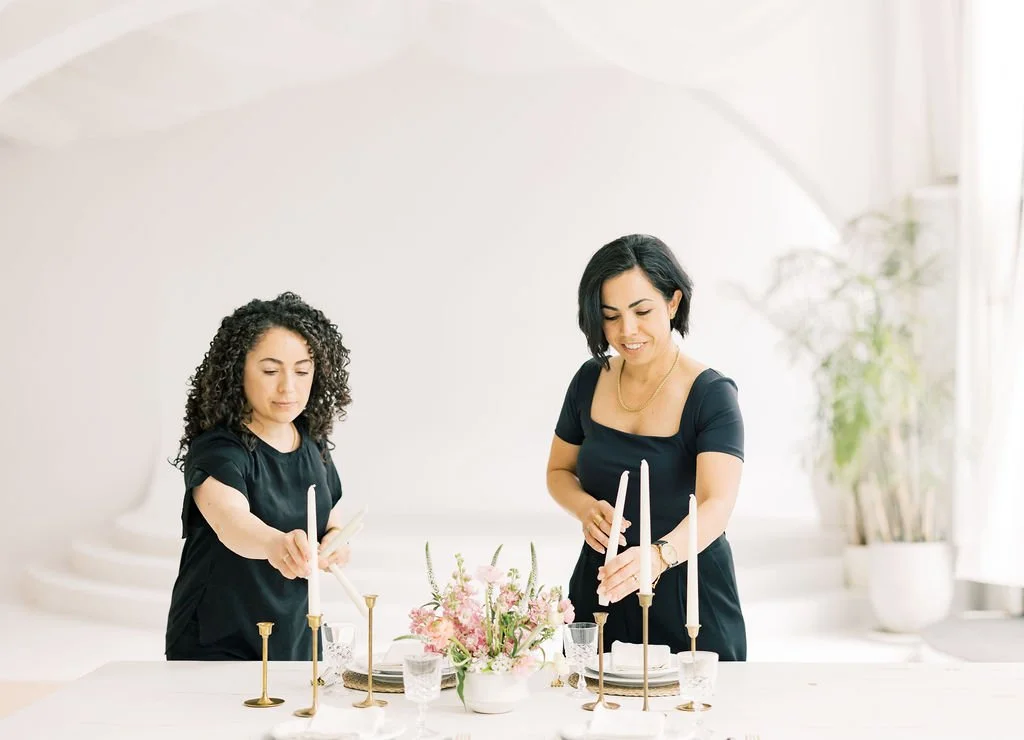 Margo Events wedding planning team arranging candles and table decor for a wedding reception.