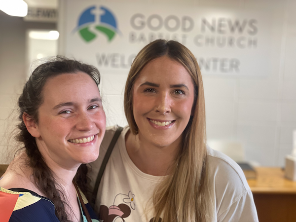 Good News Baptist Church Grand Rapids Michigan Two women smiling and standing together in front of a sign that reads 'Good News Baptist Church Welcome Center'.