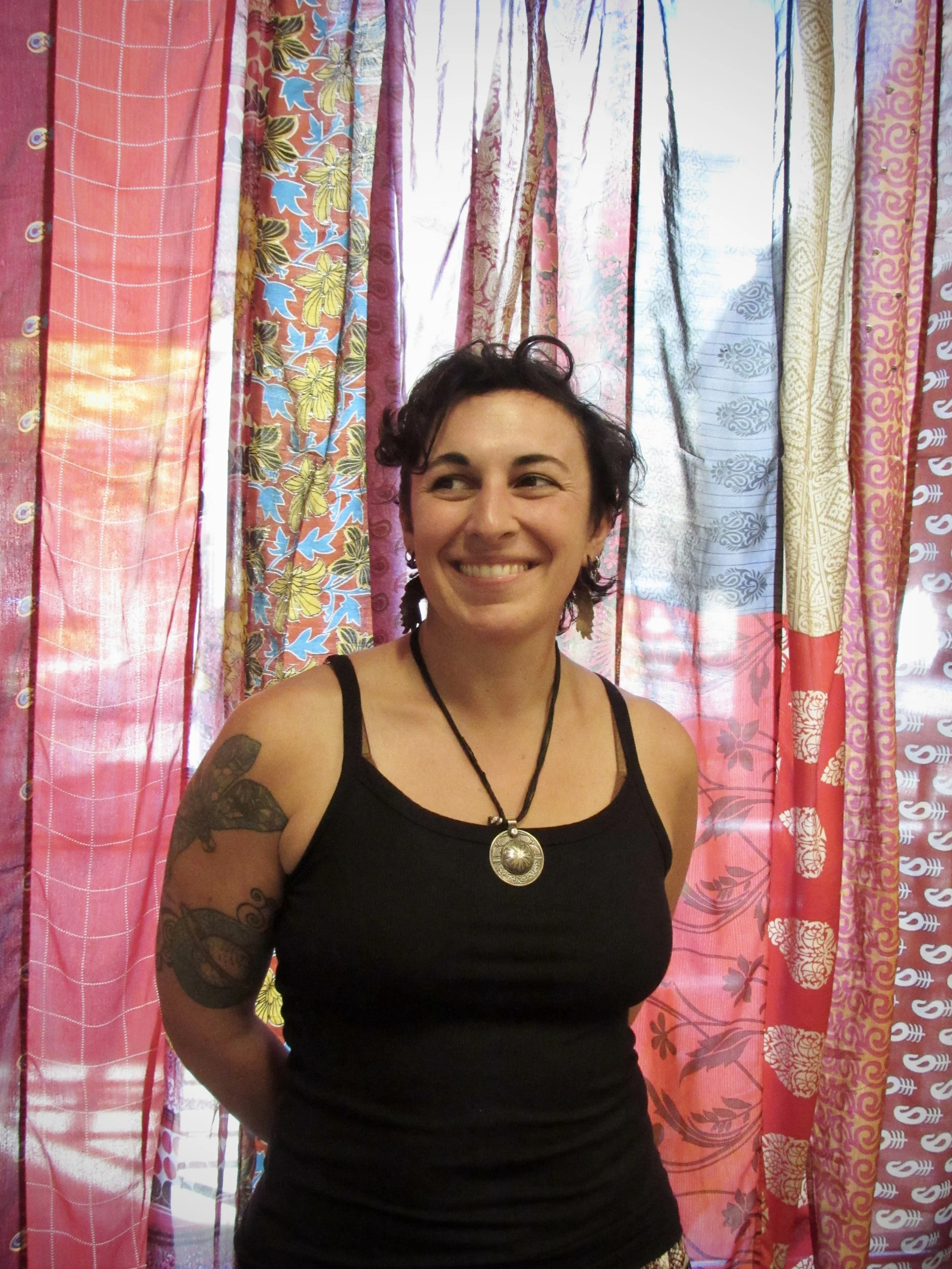 Portrait of a woman with long dark hair, smiling, wearing a black top against a neutral background.