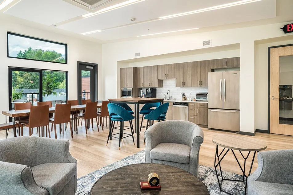 Shared lounge and kitchen area showing seating, dining tables, and the full breakroom kitchen.