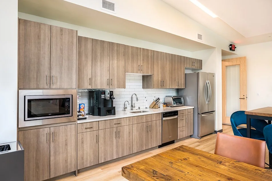 Breakroom kitchen featuring wood cabinets, stainless appliances, and a shared seating area.