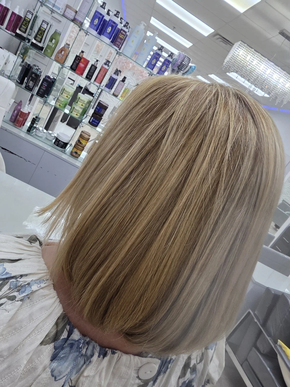 A person with straight, shoulder-length blonde hair in a salon.