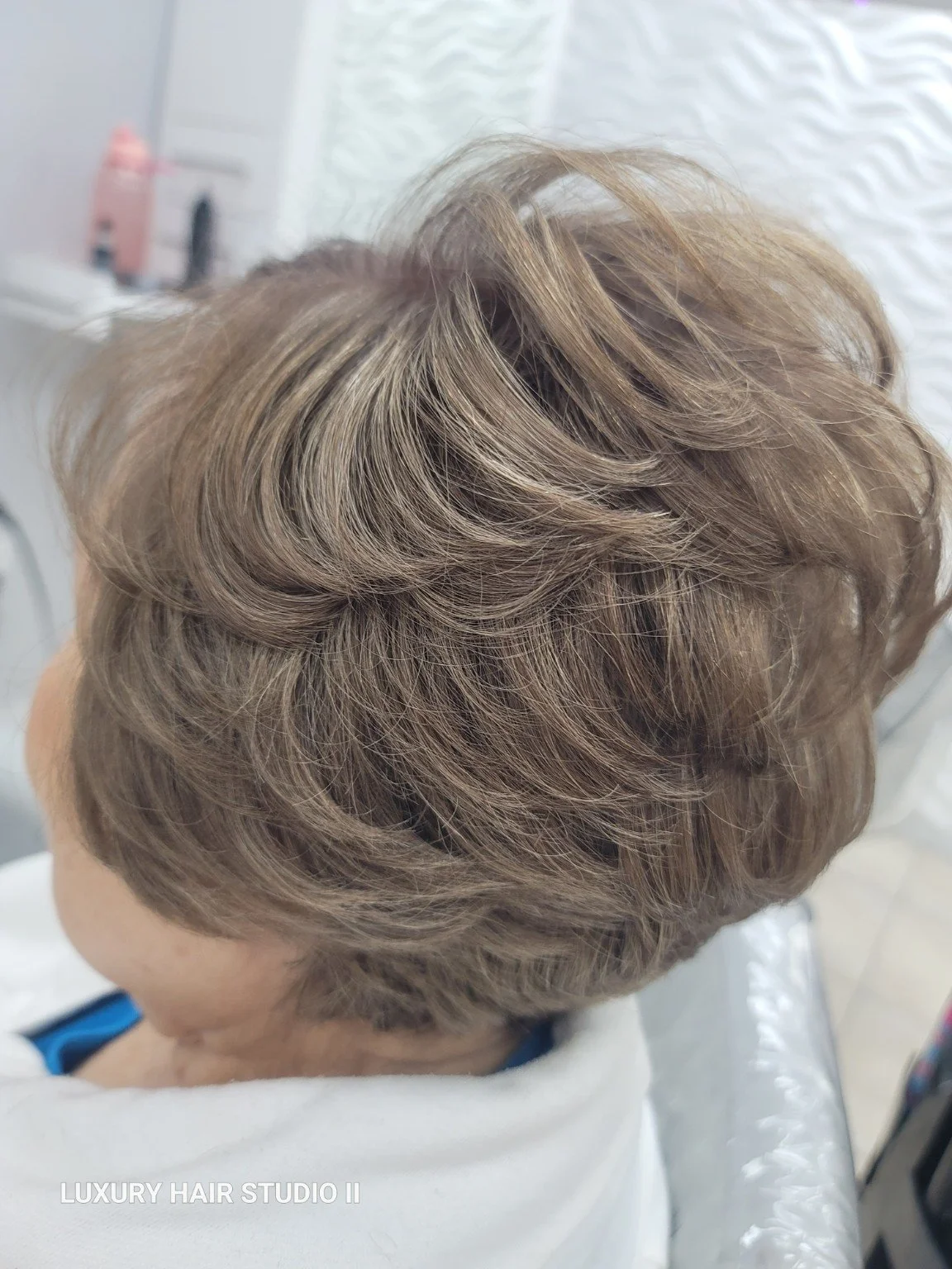 Close-up of styled short, layered, blonde hair with waves.