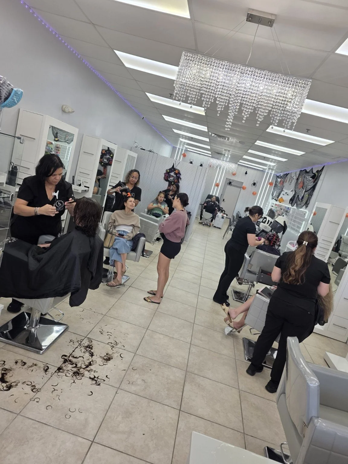 Clients and stylists inside Luxury Hair Studio II, with seasonal Halloween decorations.
